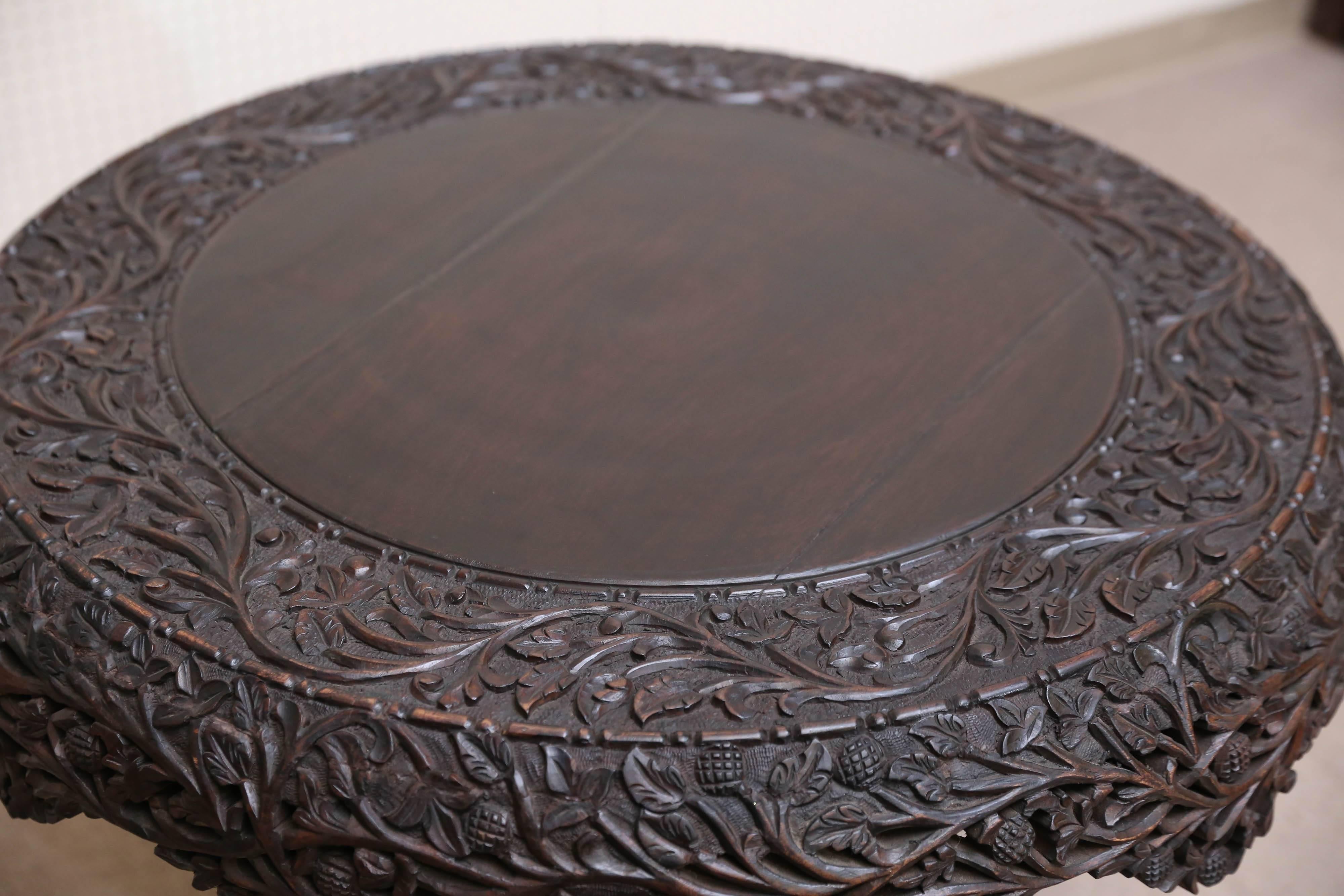 The round top edges with apron are pierce carved. It has carved round columnar support with carved square plinth and paw feet. It is an extraordinary table with precise detailed carving.