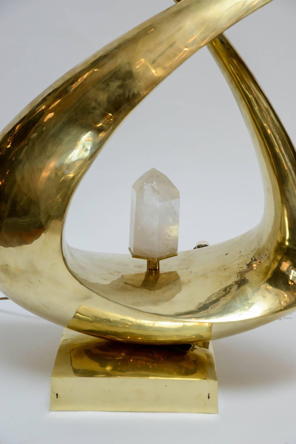 Luminous sculpture more than a lamp, this amazing piece signed by Georges Mathias is a work of art.

A one piece brass sculpture going both ways with a rock crystal in the middle diffusing the light.