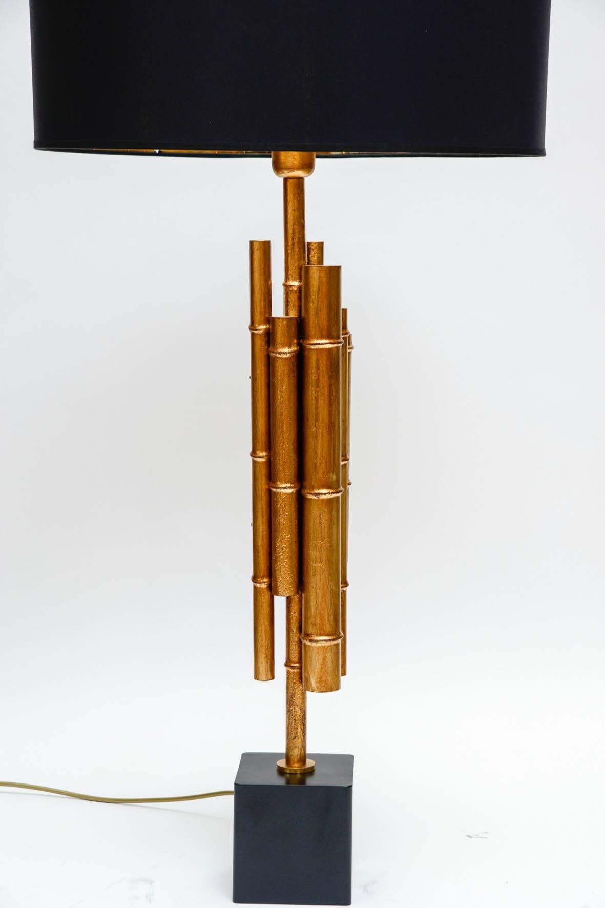 Pair of table lamps made of a black metal base and brass rods shaped like bamboo and painted.