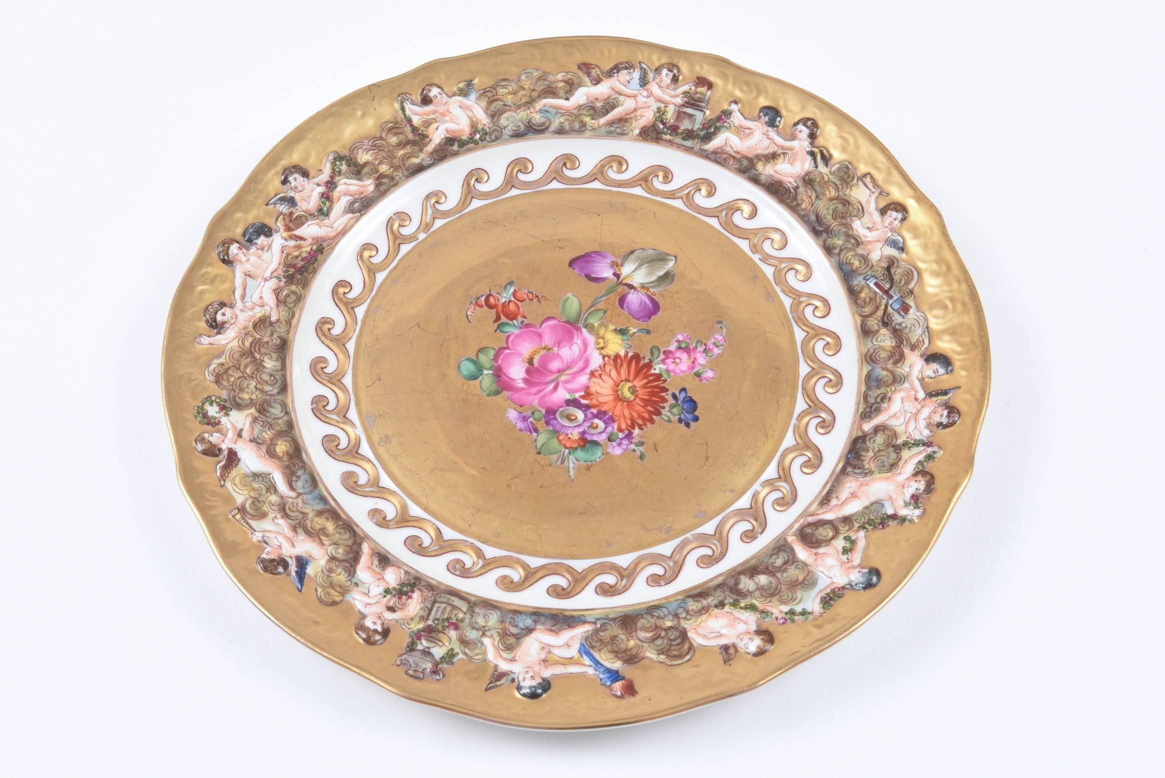So decorative with bright hand-painted florals on an all-over 24-karat gilt background. Capo Di Monte's signature raised relief putti encircling the plate on its pretty hand-painted and hand molded shoulders. As they are over 100 years old, they do