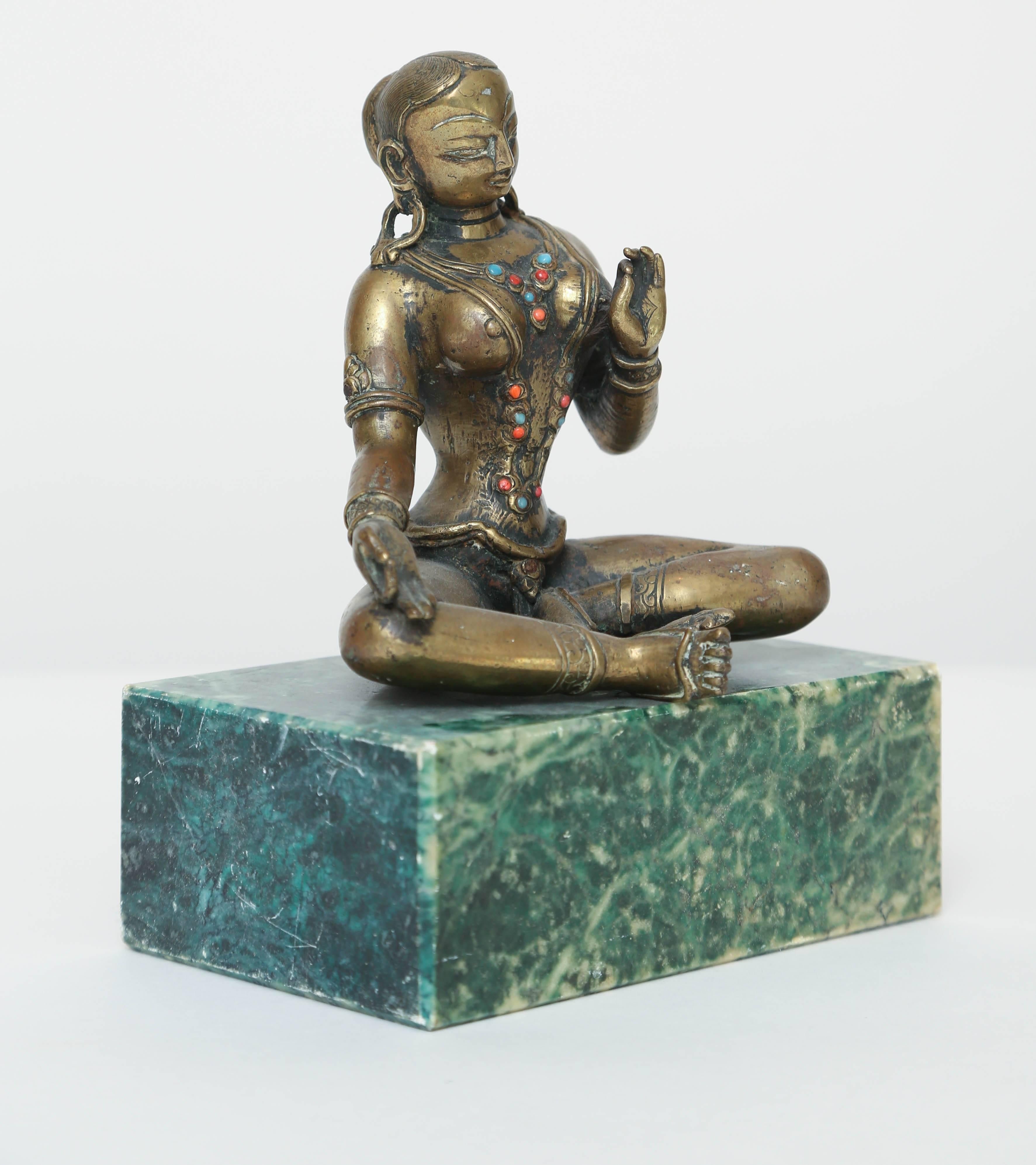 This solid cast bronze statuette depicts the Hindu goddess Tara as she sits with legs folded holding her hands in the gran mudra position which is said to bring peace, calm and spiritual progress. She is adorned with necklaces, armbands and