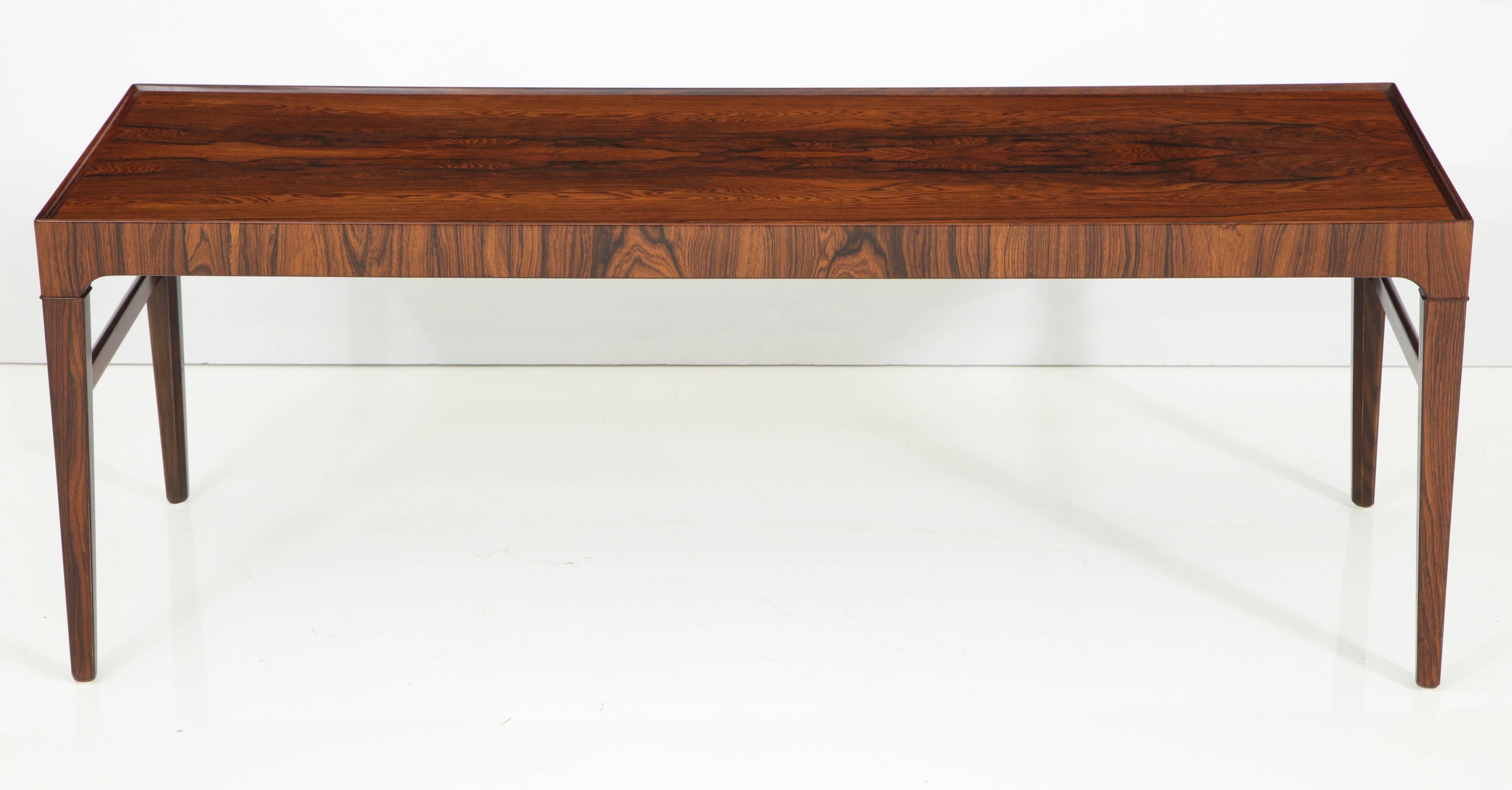 A beautifully grained rosewood coffee table, Danish, circa 1960s, a rectangular top with channeled edge raised on square tapered legs.