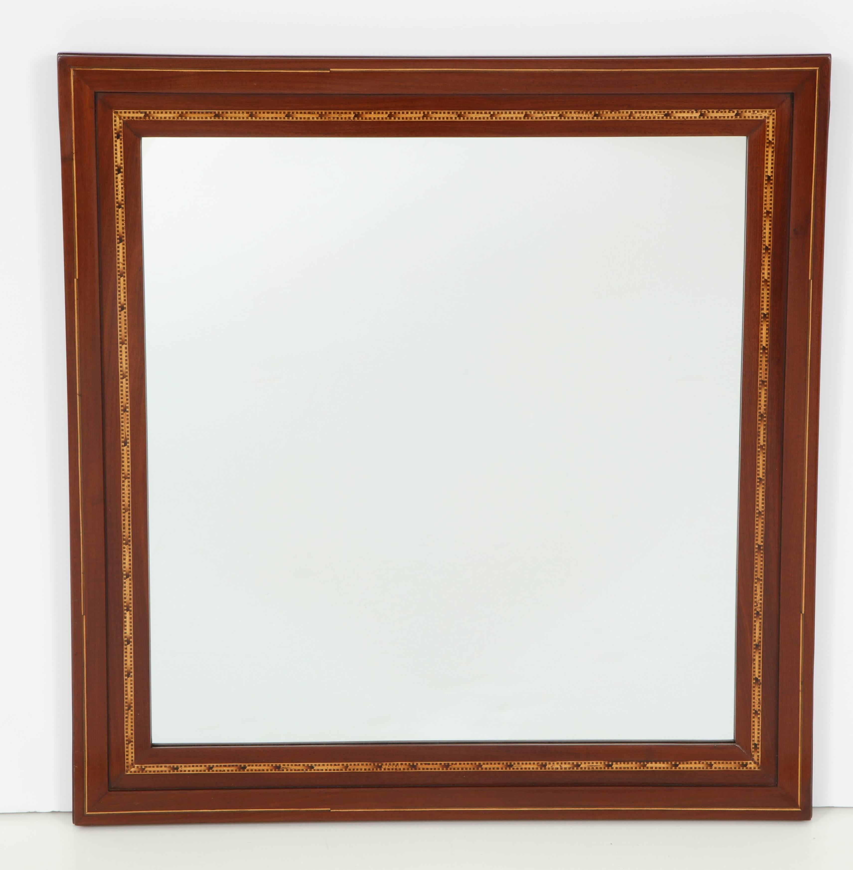 A Danish fruitwood inlaid mahogany mirror, circa 1910, with a flat and profiled frame inlaid with geometric fruitwood. New mirror glass.