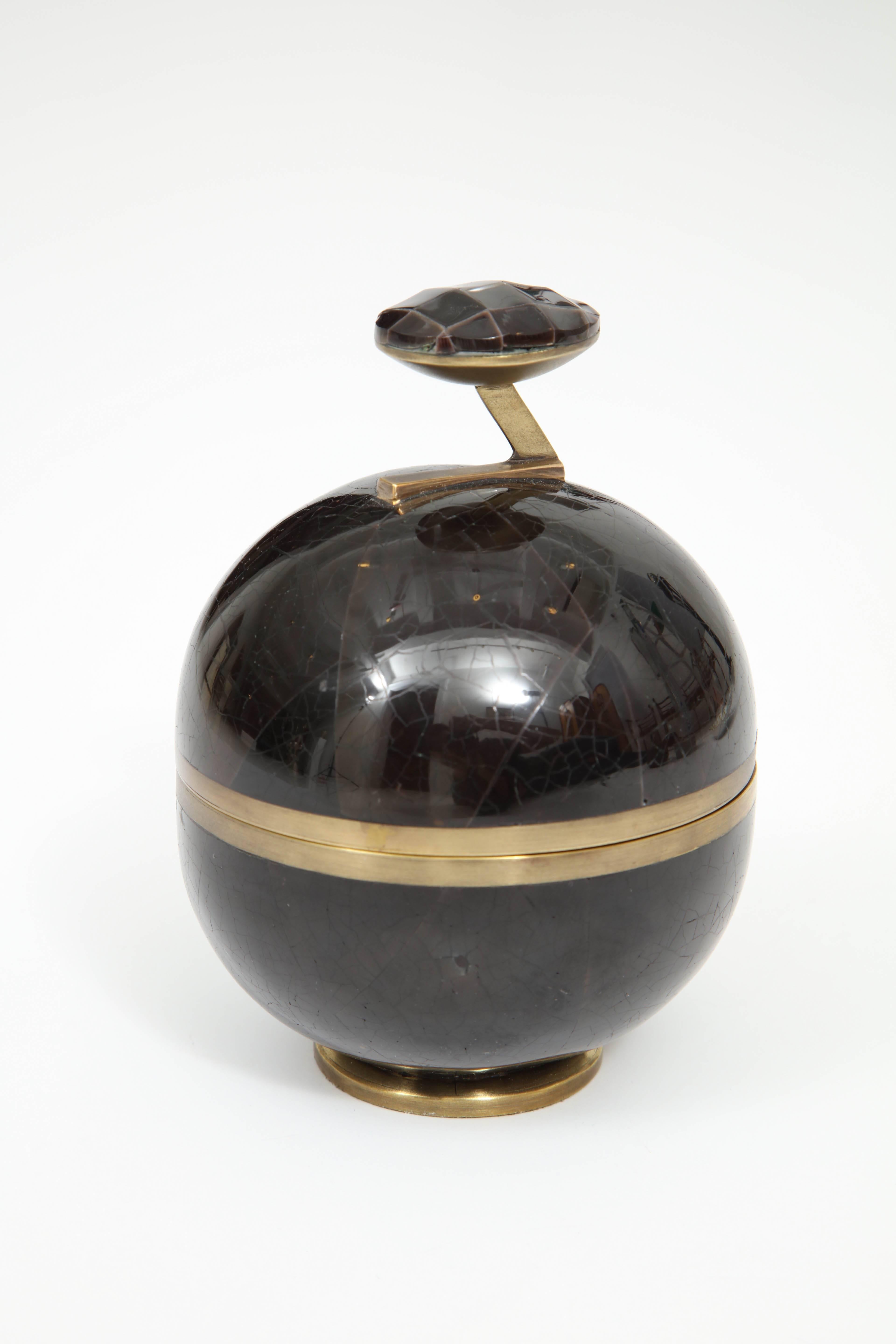 Decorative round box made of black seashells and bronze.