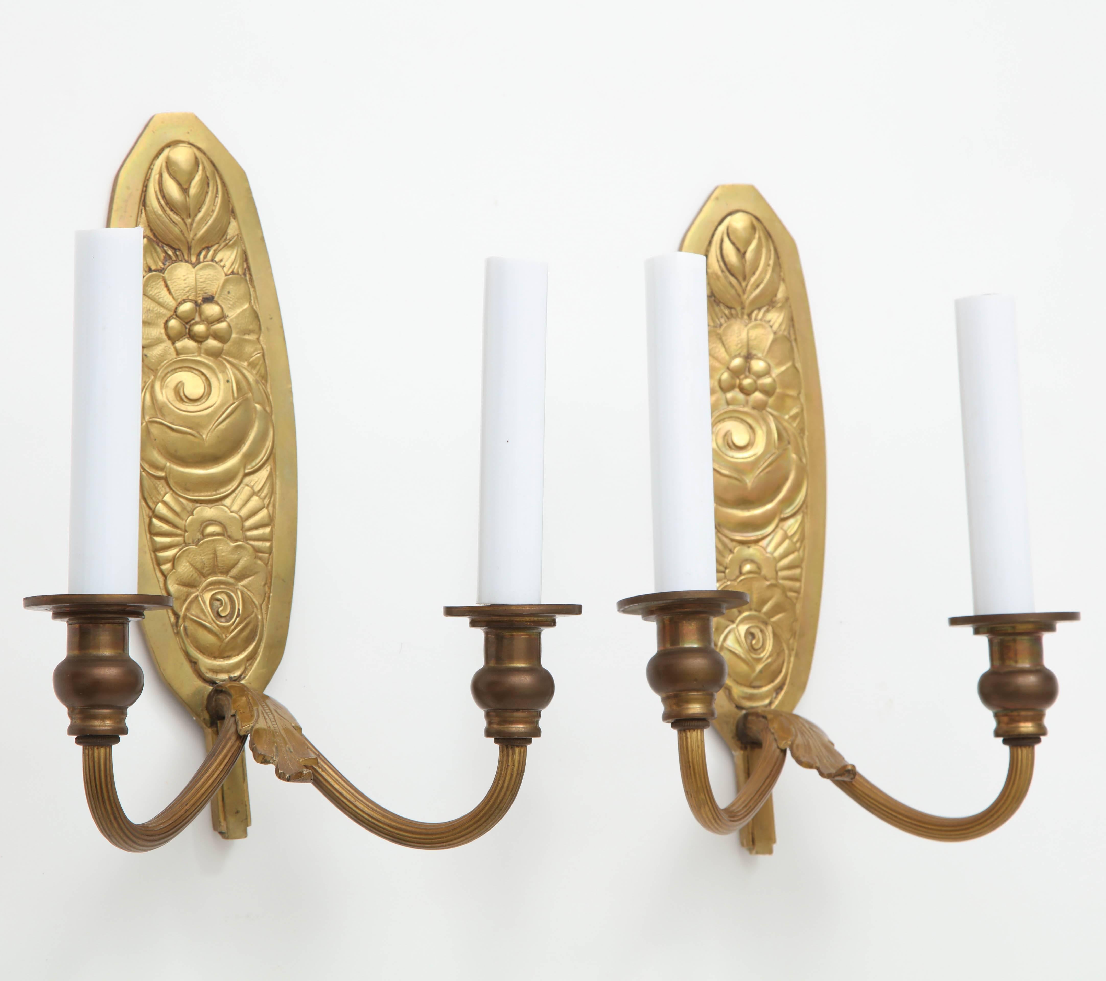 Pair of very fine bronze wall mount candle sconces or candleholders, each with two arms, and featuring a richly embossed backplate having a floral design. France, circa 1930-1940, possibly older.

Sconces are not electrified; shown in photo with