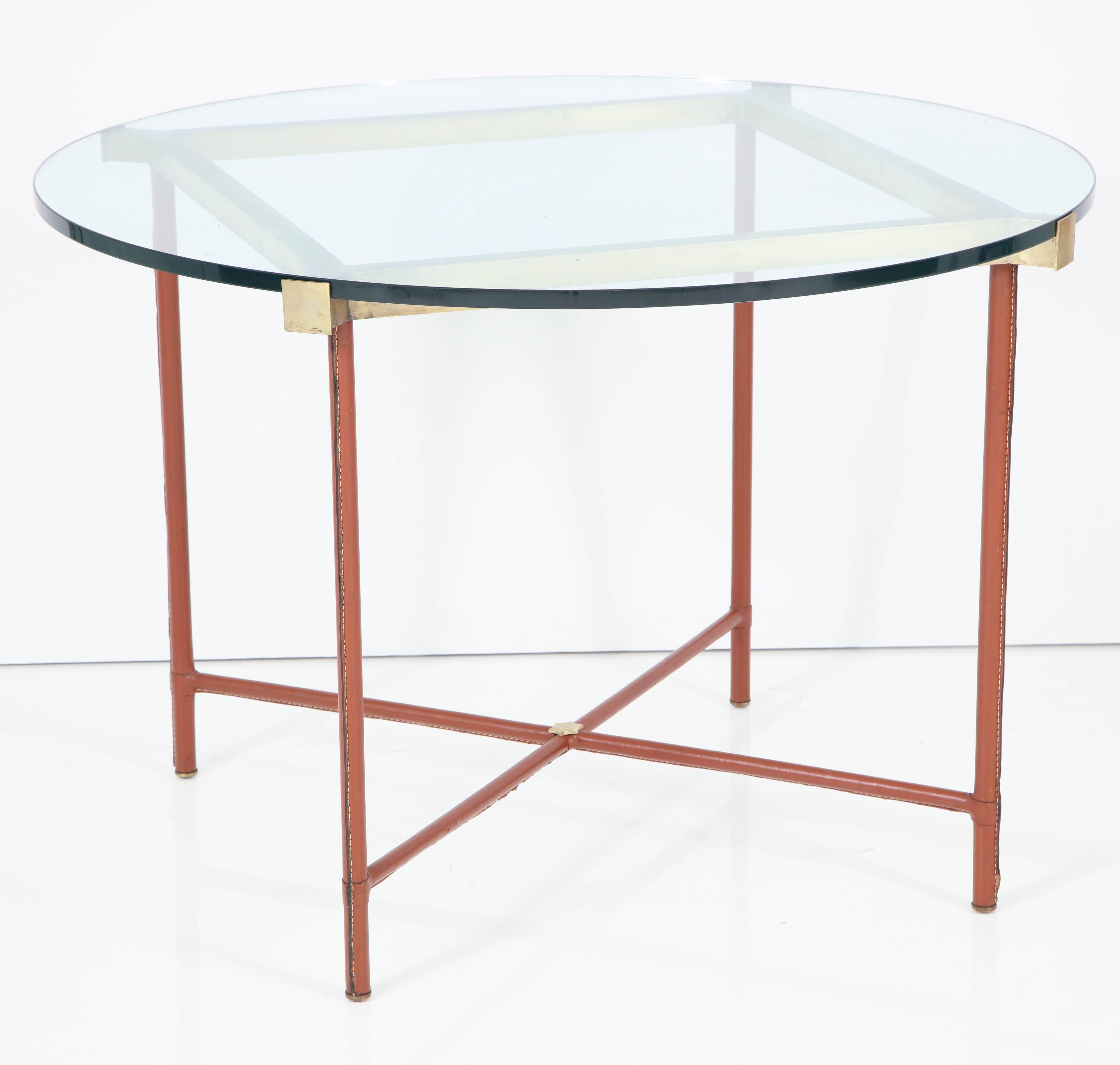 Elegant centre table by Jacques Adnet, metal frame covered in hand-stitched leather, brass hardware and frame. Glass top.