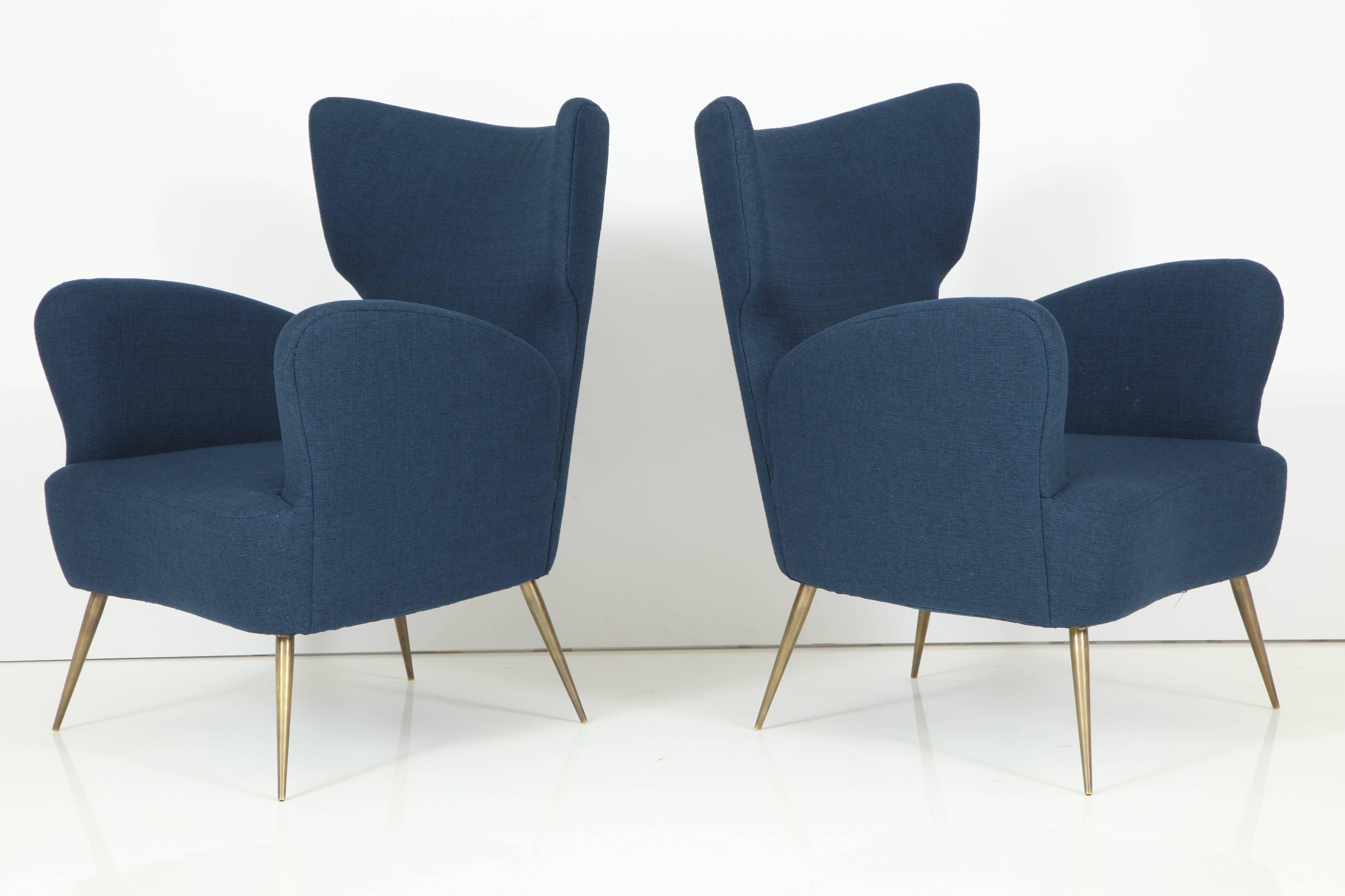 Pair of Italian wingchairs upholstered in blue cotton, on brass legs. Very comfortable.