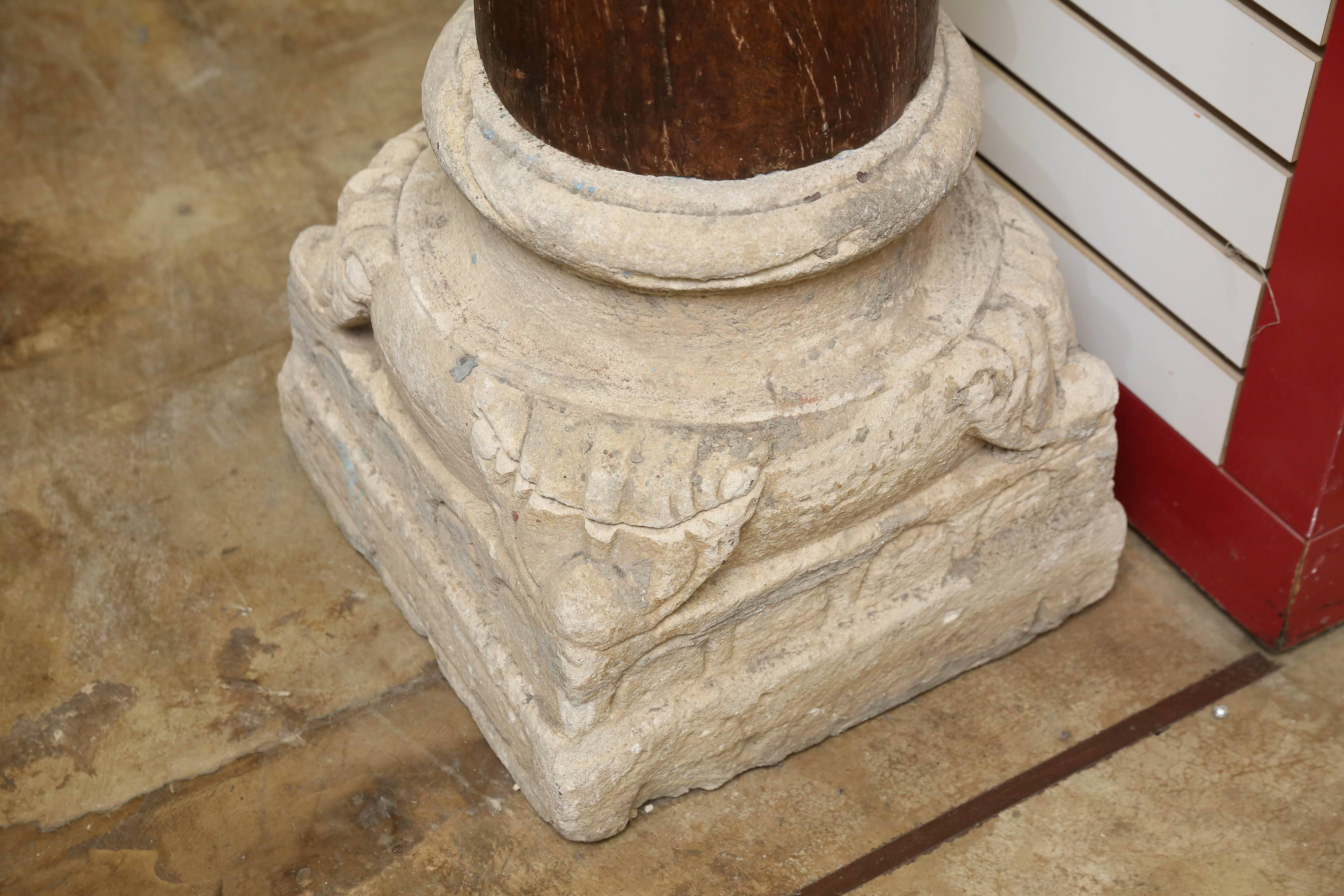 Pair of 1820s solid teak wood load bearing columns with solid teak wood crowns supported on hand-carved sandstone bases. These columns once carried a two storied colonial mansion. Since these columns supported the slanting roof of the front porch