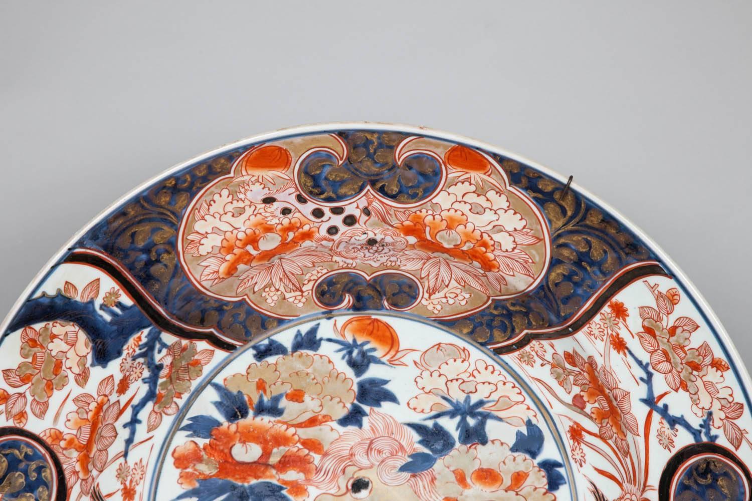 A richly decorated large imari charger from Japan, circa 1700. The centre with a composition of a kara shi-shi gambolling amongst flowers. The broad rim decorated with panels depicting further kara shi-shi lions at their leisure. The charger is