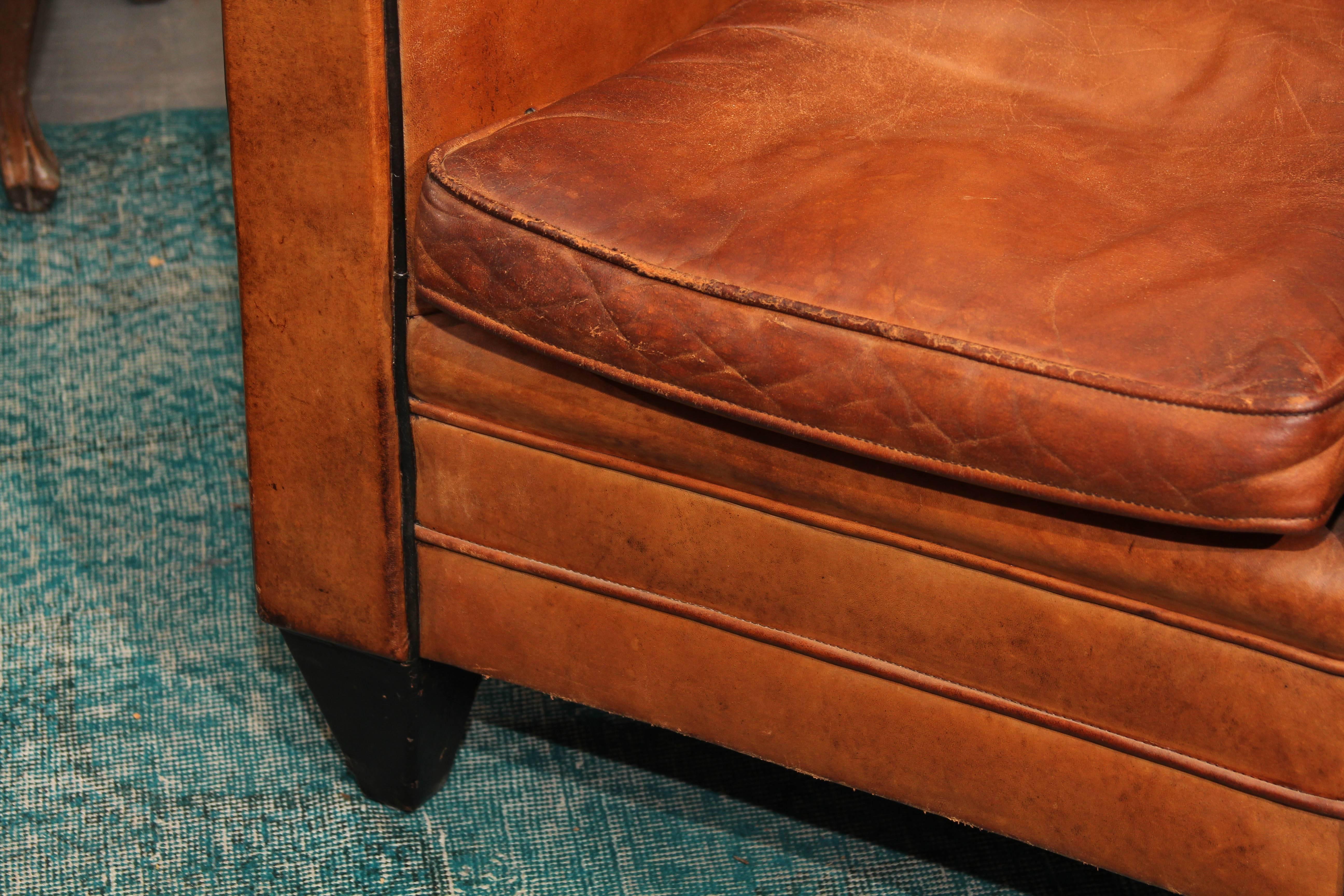 Pair of unusual even-arm European Art Deco club chairs circa 1937 in rich caramel leather with black piping and black leather-wrapped foundations. Handsome from every angle, very comfortable, very handsome.
 