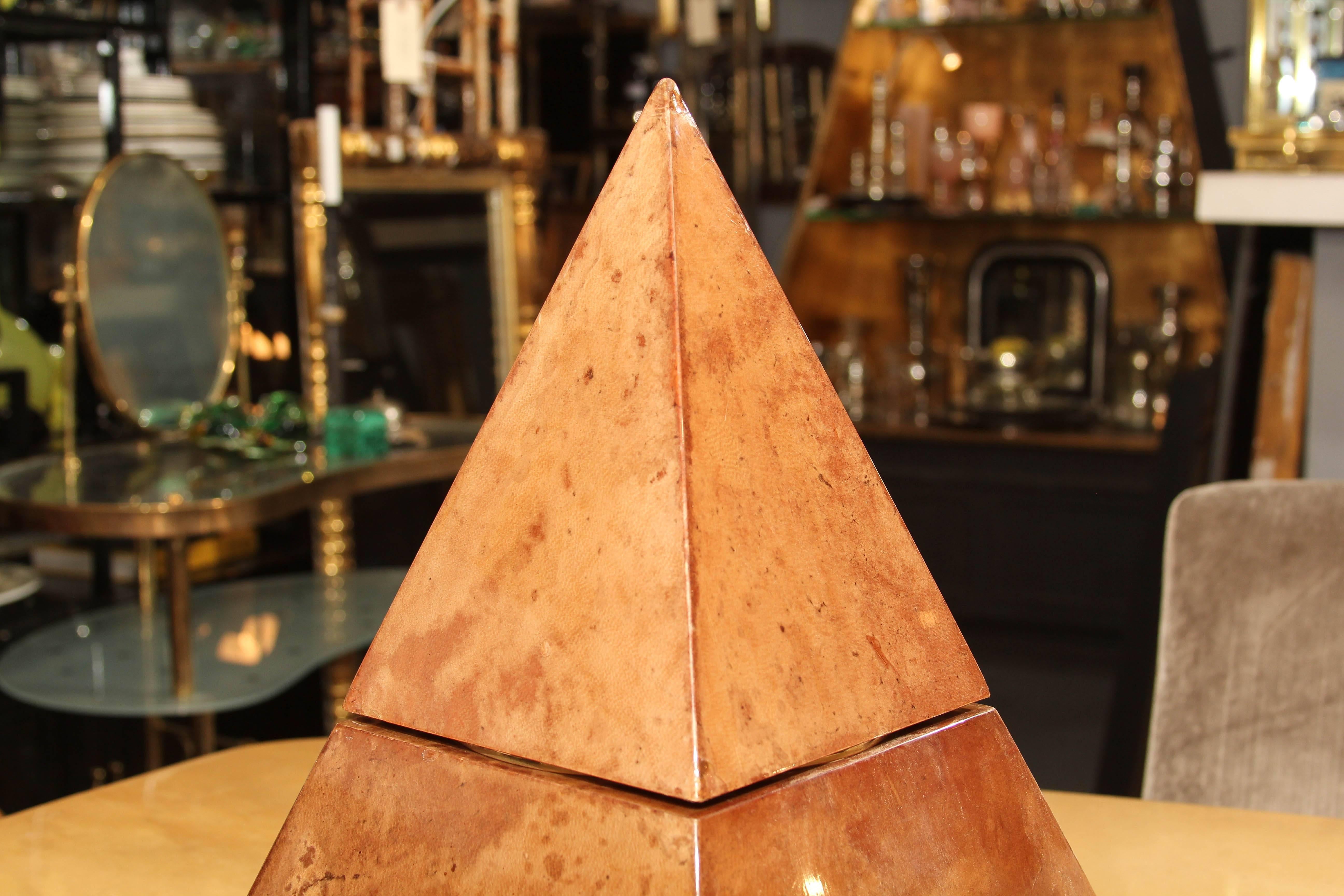 Der Eiskübel, ein seltenes Design von Aldo Tura, ist mit cremefarbenem, lackiertem Ziegenleder überzogen, das insgesamt eine wunderschöne Patina aufweist. Der Behälter selbst ist aus weißem Kunststoff. Die Pyramidenform bietet einen überzeugenden