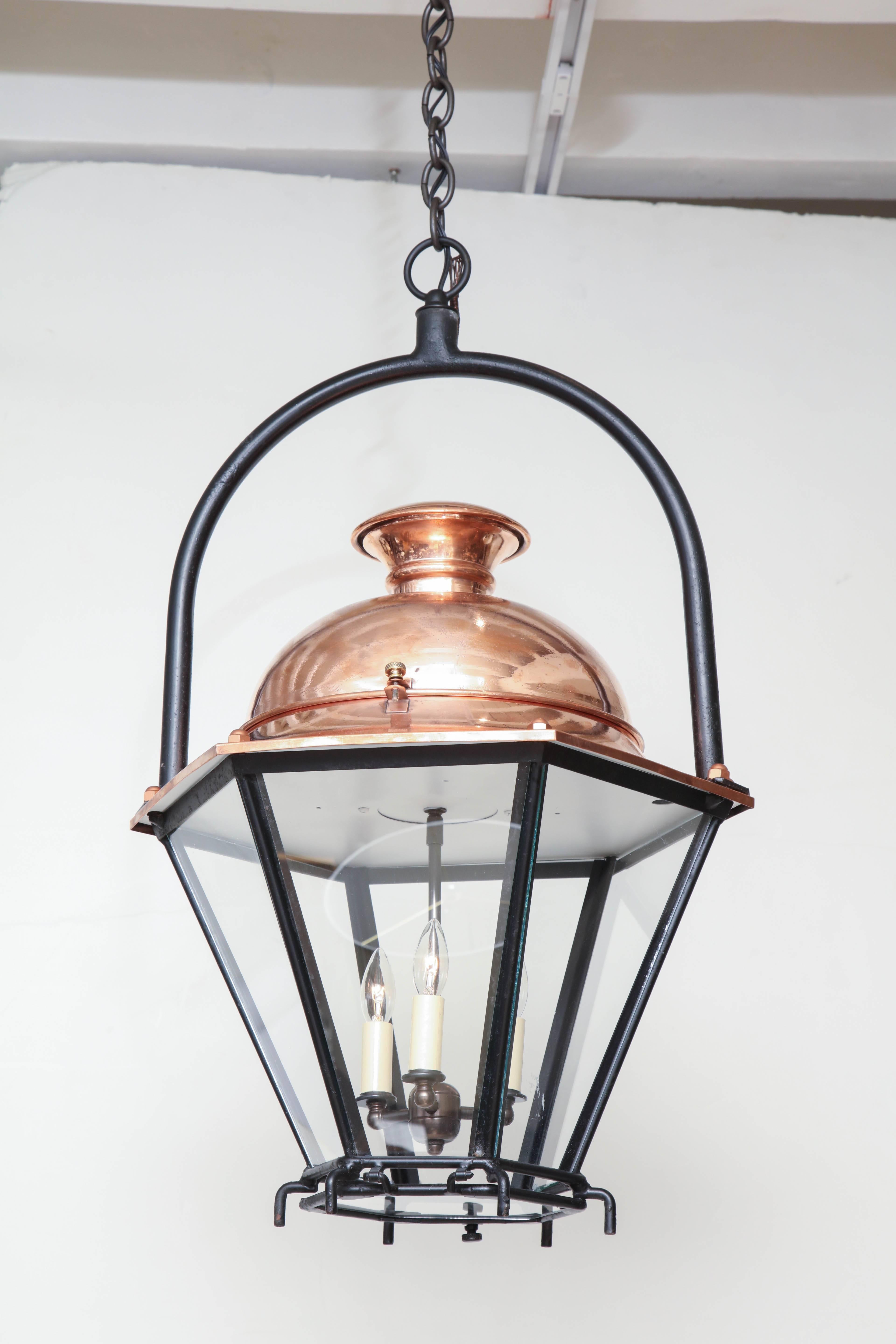 An early 20th century hexagon shaped lantern with six glass panels and a polished, unlacquered copper top. Hung from an iron ring hanger. Contains three candelabra style light sockets, recently rewired for US specifications.



Available to see in
