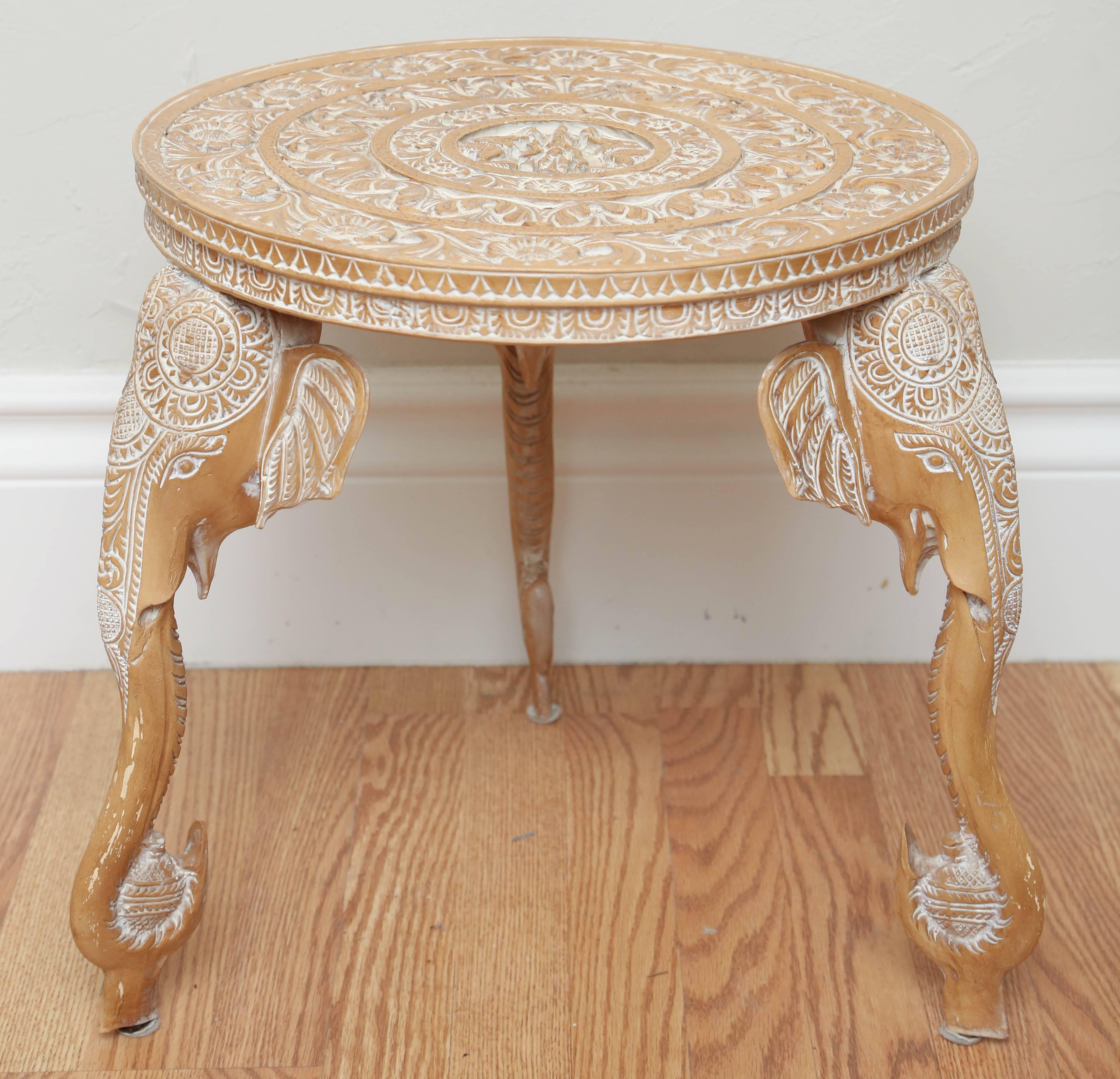 White washed round elephant end table with three trunks supporting top.