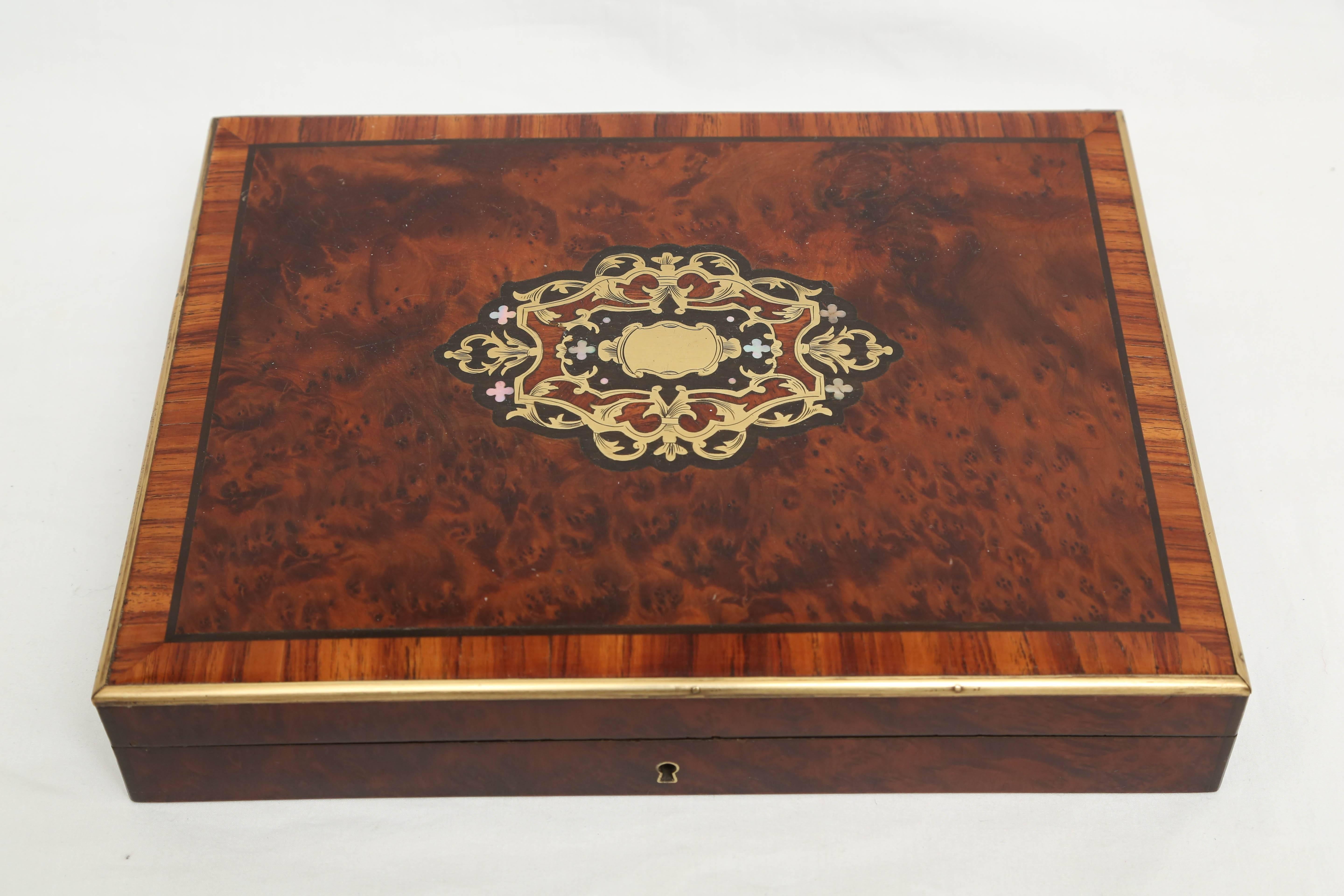 This slightly domed top box is appointed with brass and mother-of-pearl inlays.
In addition the burl wood top is crossbanded with a brass border.
Exquisite quality and workmanship.
It contains over 100 bone playing chips. The card deck of 37