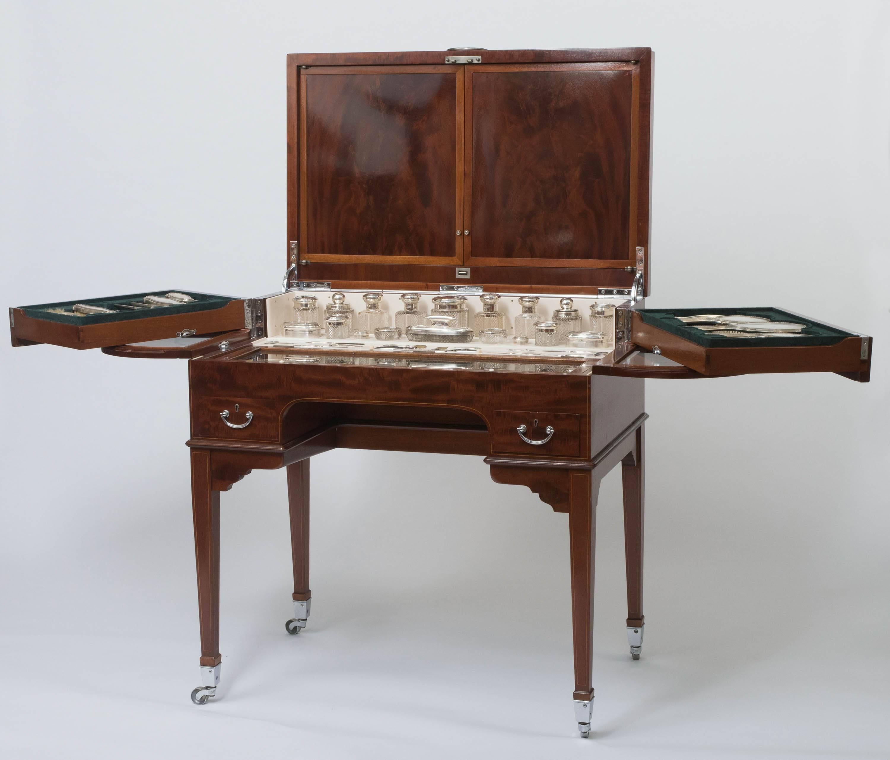 Dressing table by George Betjeman and Sons, beautifully veneered in flame mahogany with boxwood stringing. 
Fitted interior of forty three matching silver gilt and crystal dressing items. 
Registration number no. 532586
England, circa 1911
fully