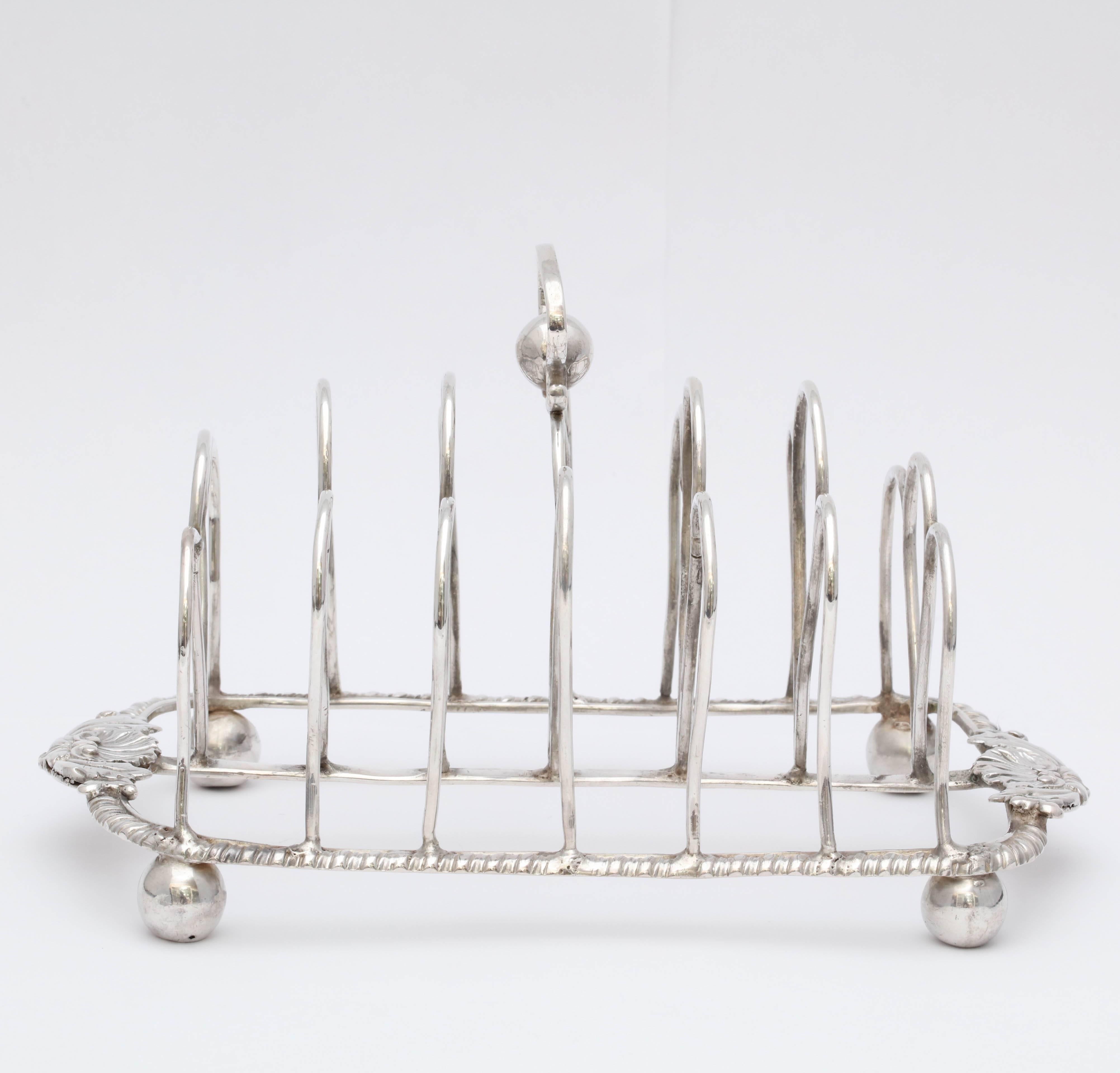 Georgian (George IV), sterling silver toast rack, on ball feet, London, 1811. 7 1/4 inches long x 4 3/4 inches high (to top of handle) x 4 inches deep. Ball feet have been flattened on the underside (original to piece). Minor dints commensurate with