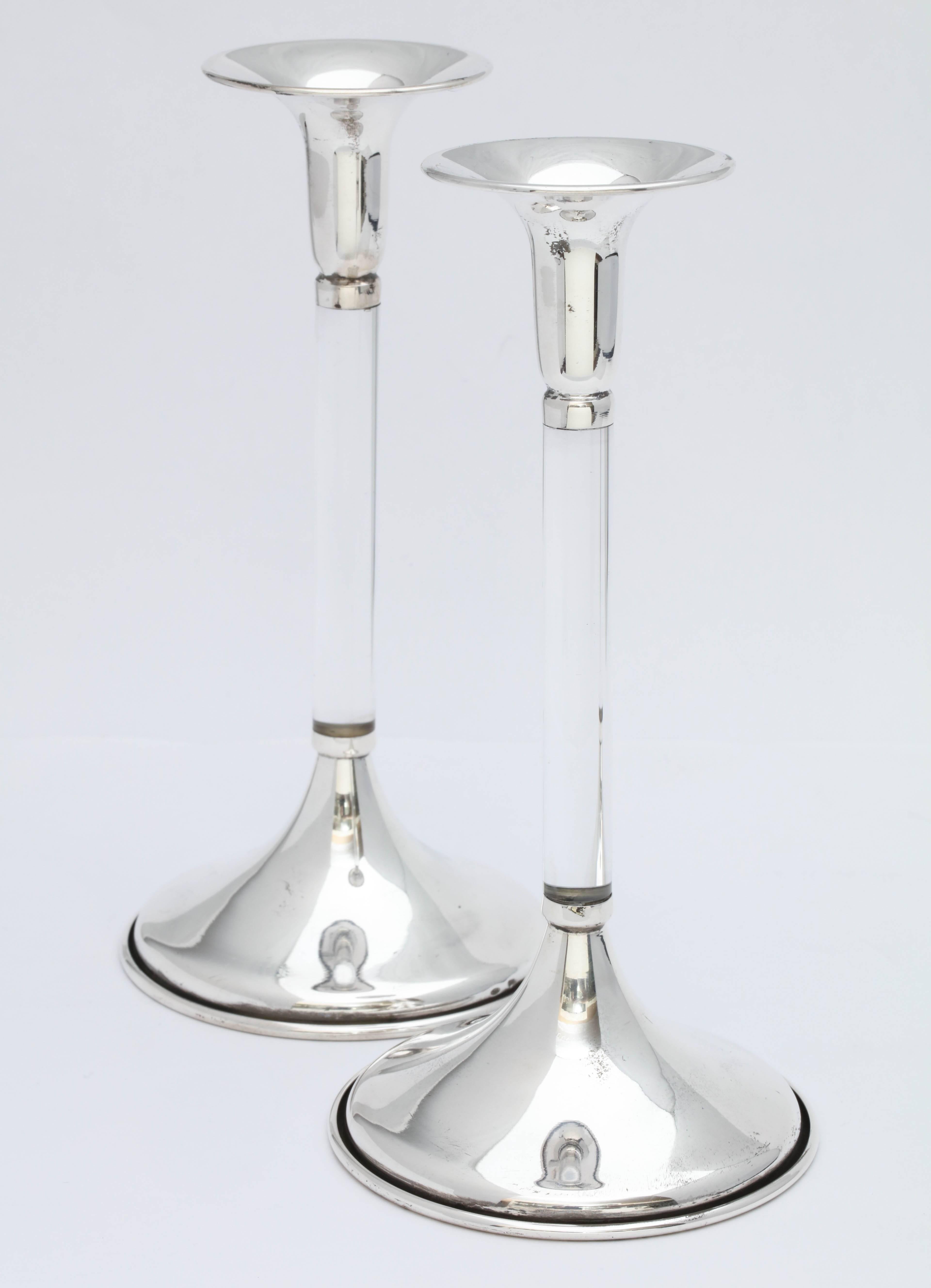 Pair of Mid-Century Modern, sterling silver-mounted Lucite candlesticks, European, circa 1950s-1960s. 7 inches high x 3 1/2 inches diameter across base of each x 2 inches diameter across sterling silver candle cup. Weighted; underside of each is