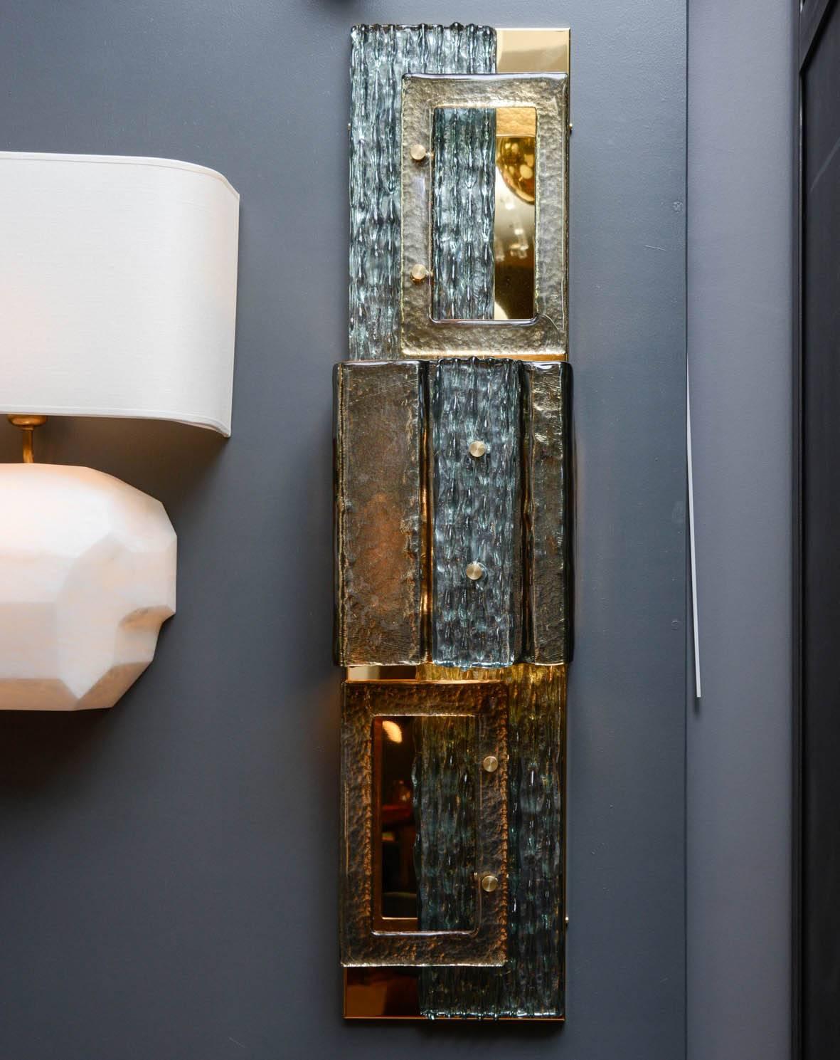Rectangular tall wall sconces made of brass with different overlayed Murano glass panels.

Four lights per sconce.