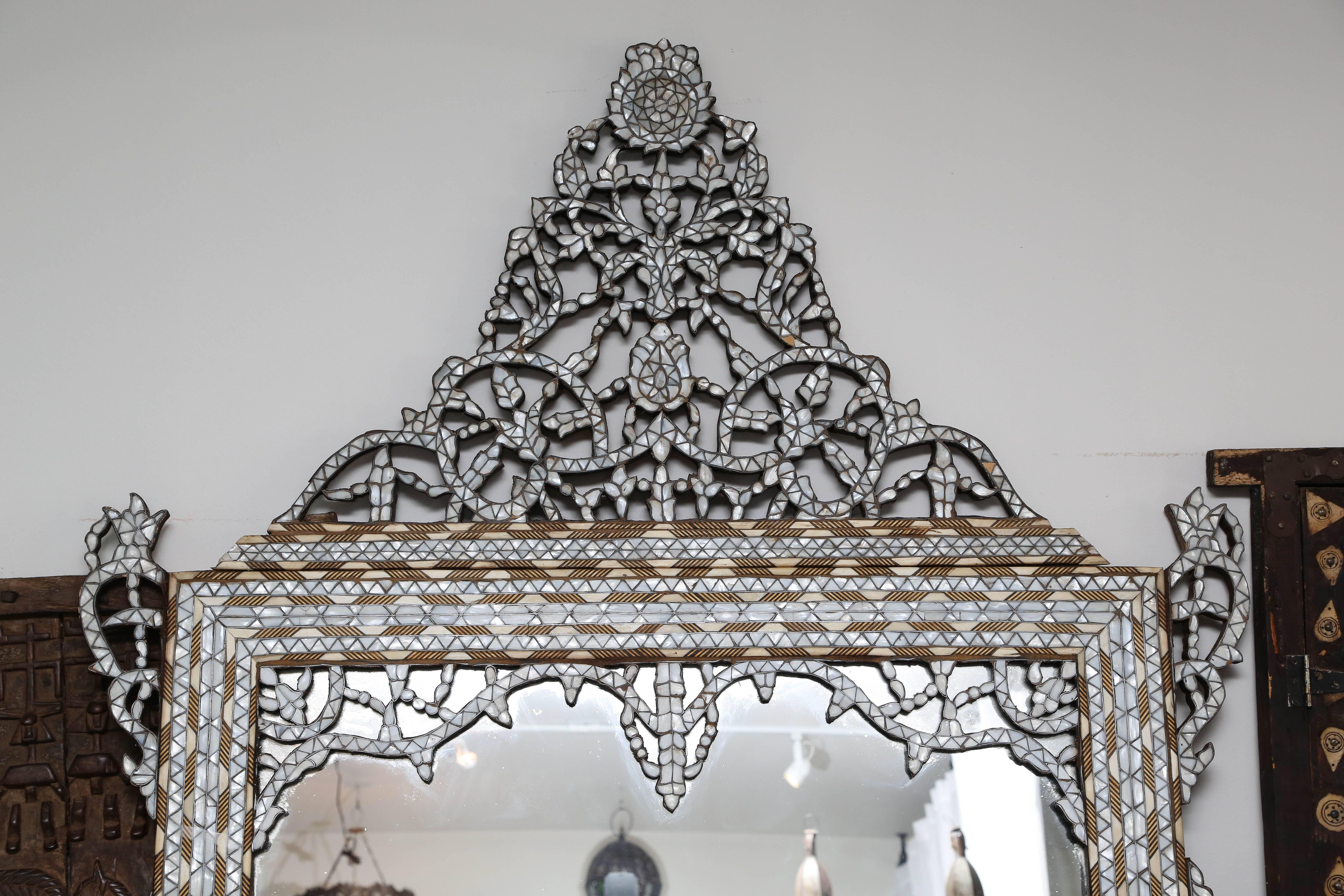 This antique handcrafted inlaid mirror is crafted from individuality cut pieces of mother-of-pearl and camel bone. The high bonnet top is geometric style design is detachable for easy transport.