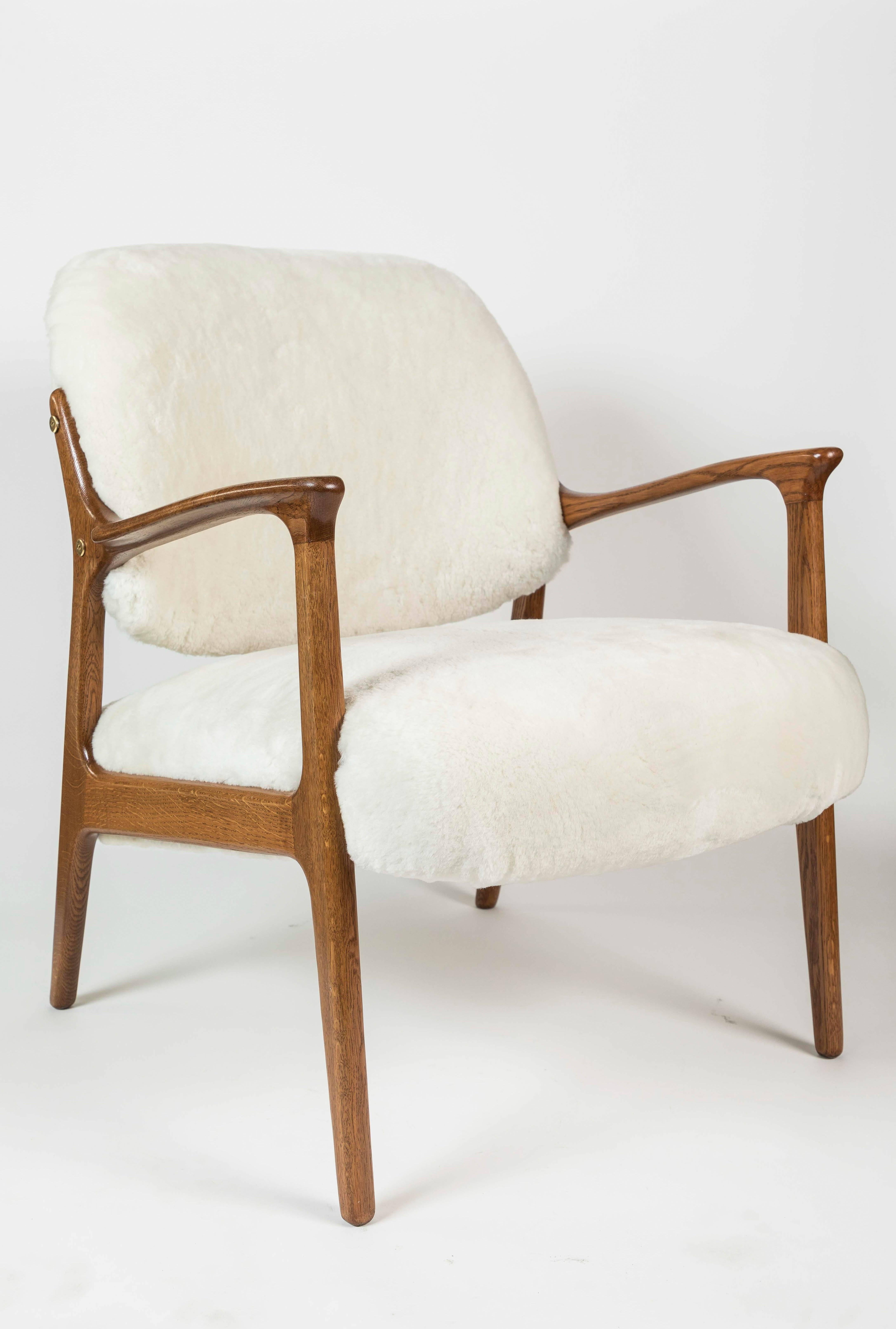 Pair of newly refinished midcentury teak framed arm chairs that are newly upholstered in white shearling.

Measure: arm height 23.5".