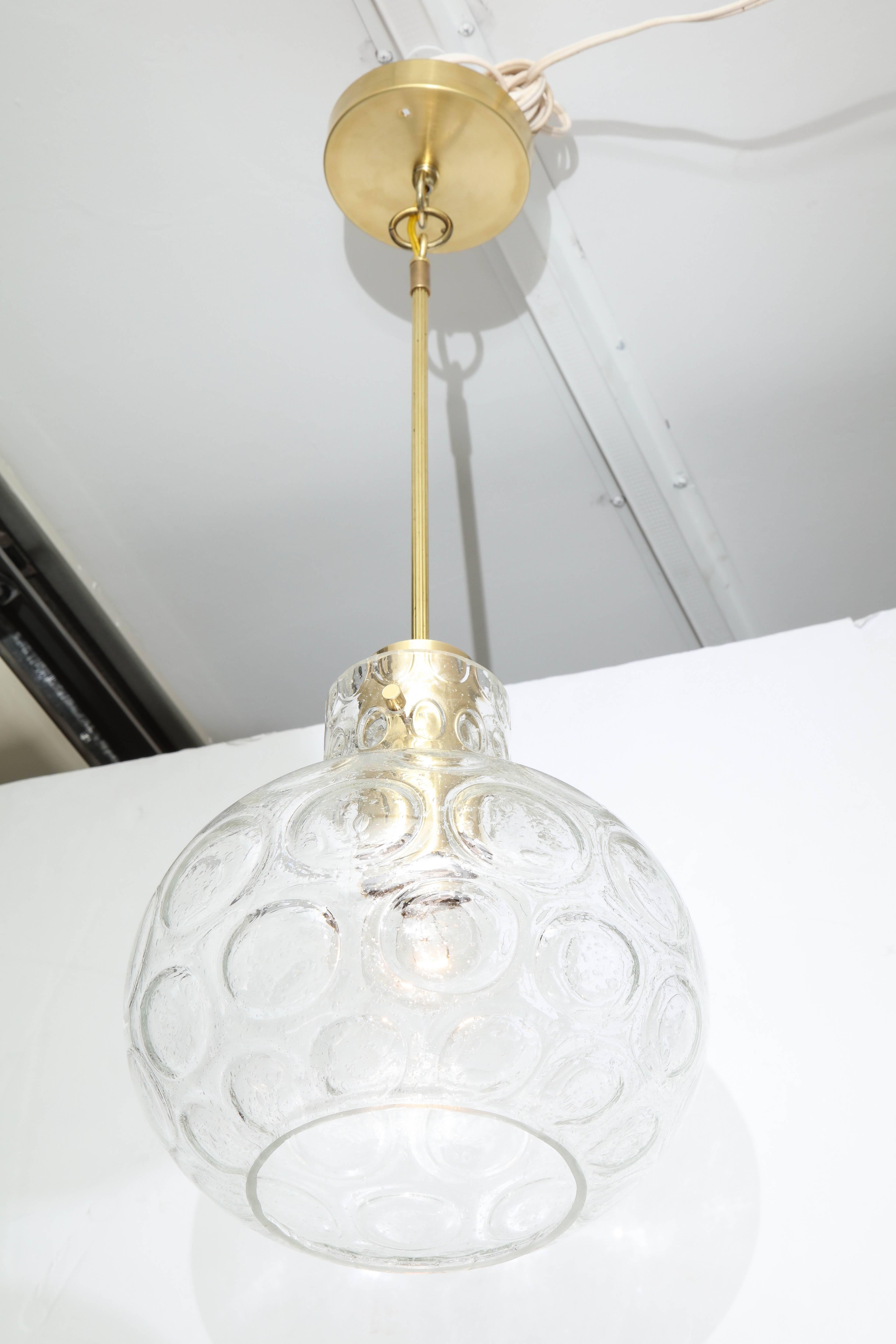 Pair of beautiful pendant lights by Doria.
The blown glass has an incised circle deign and is supported by polished brass hardware. 
The fixtures come with a 12