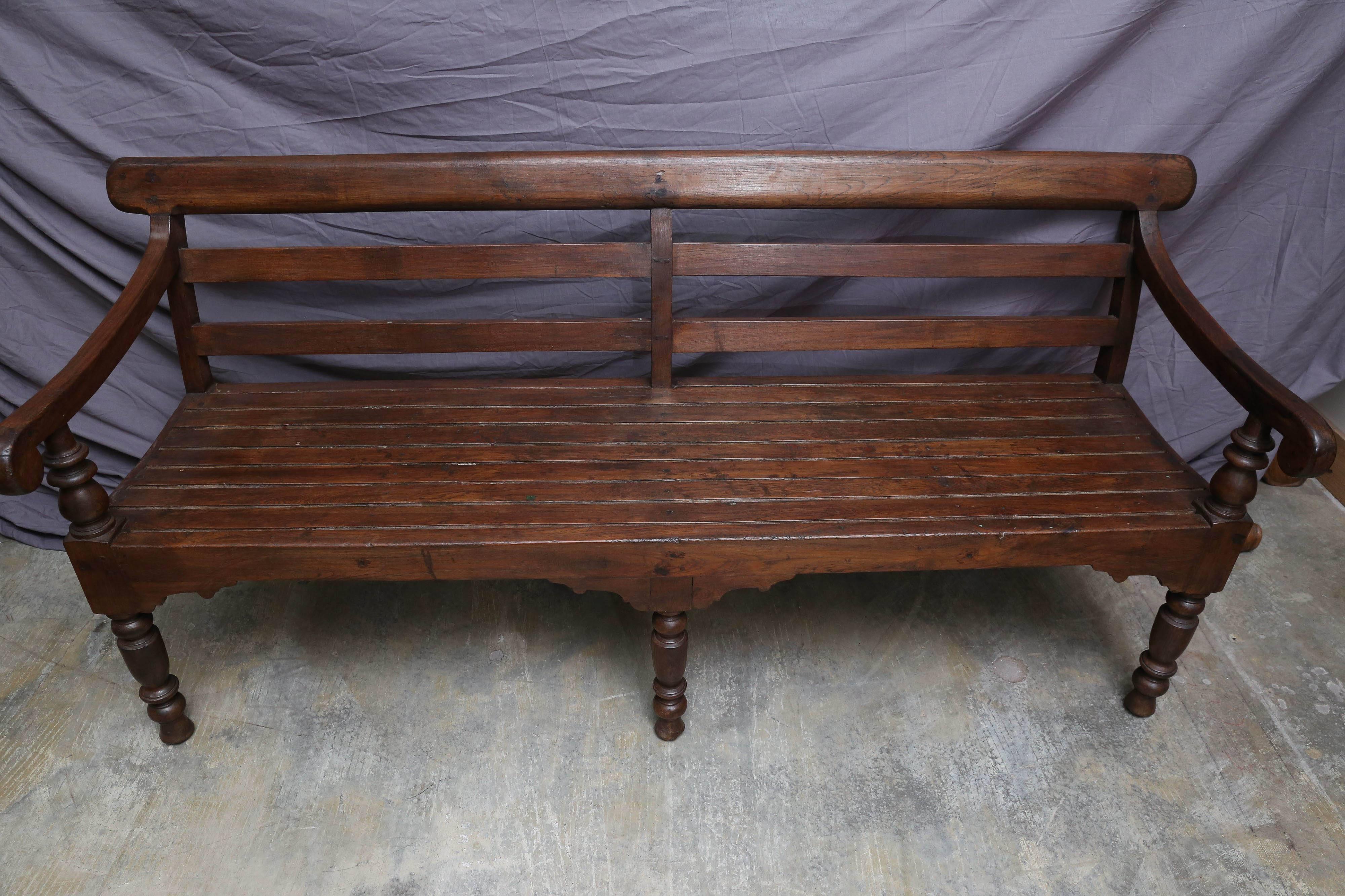 This simple bench is made of solid teak wood, contoured for comfort and is supported by six carved legs. It comes from a colonial tea plantation. It is made in the old world style of carpentry and has a rich wood patina. These benches have weathered