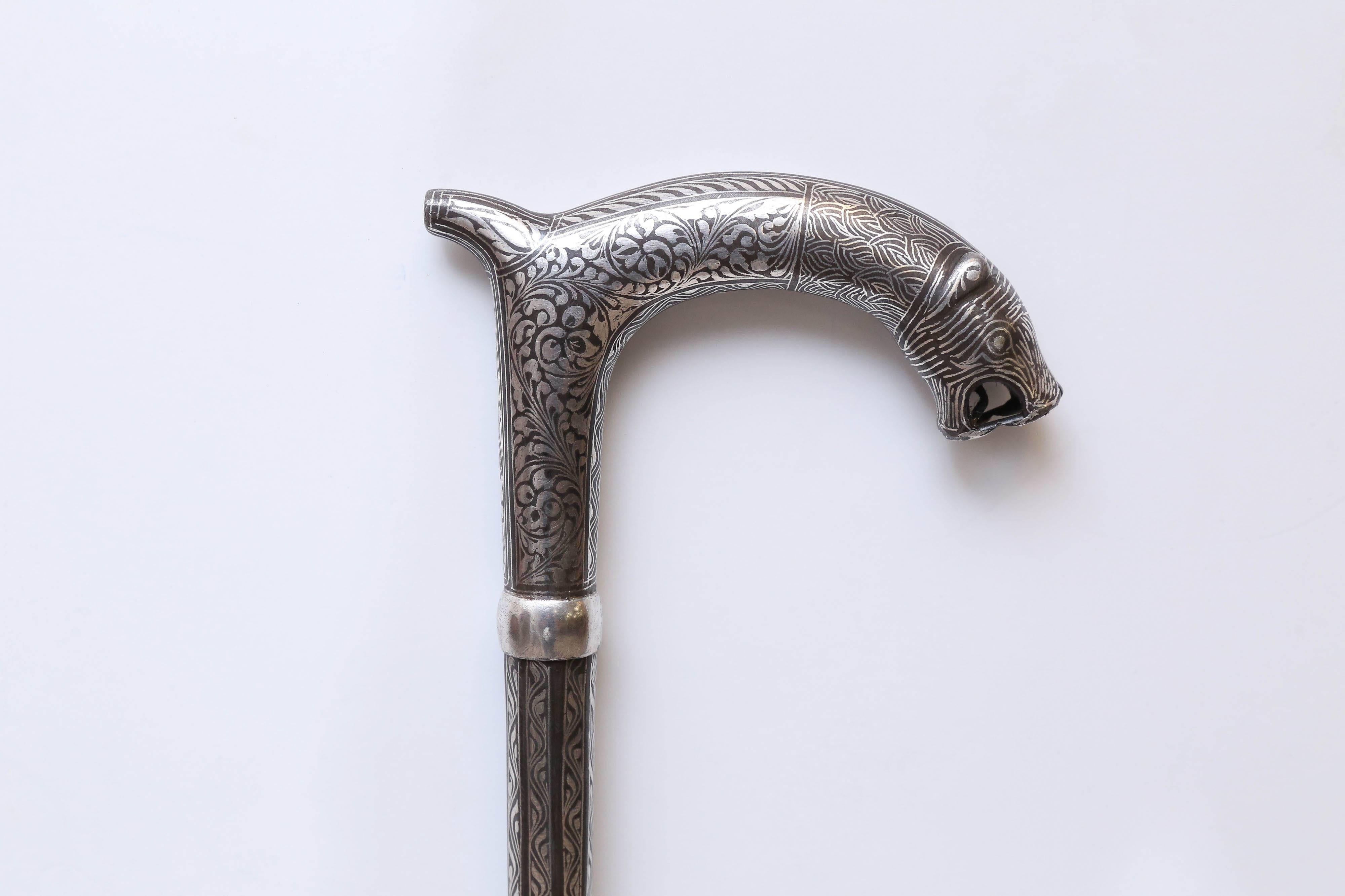 A great Christmas presentation piece. Intricate silver filigree work on iron highlight this unique walking stick. It has a long decorative knife inside. It is 37" long and 1" diameter at the handle. The bottom three inches is all silver.
