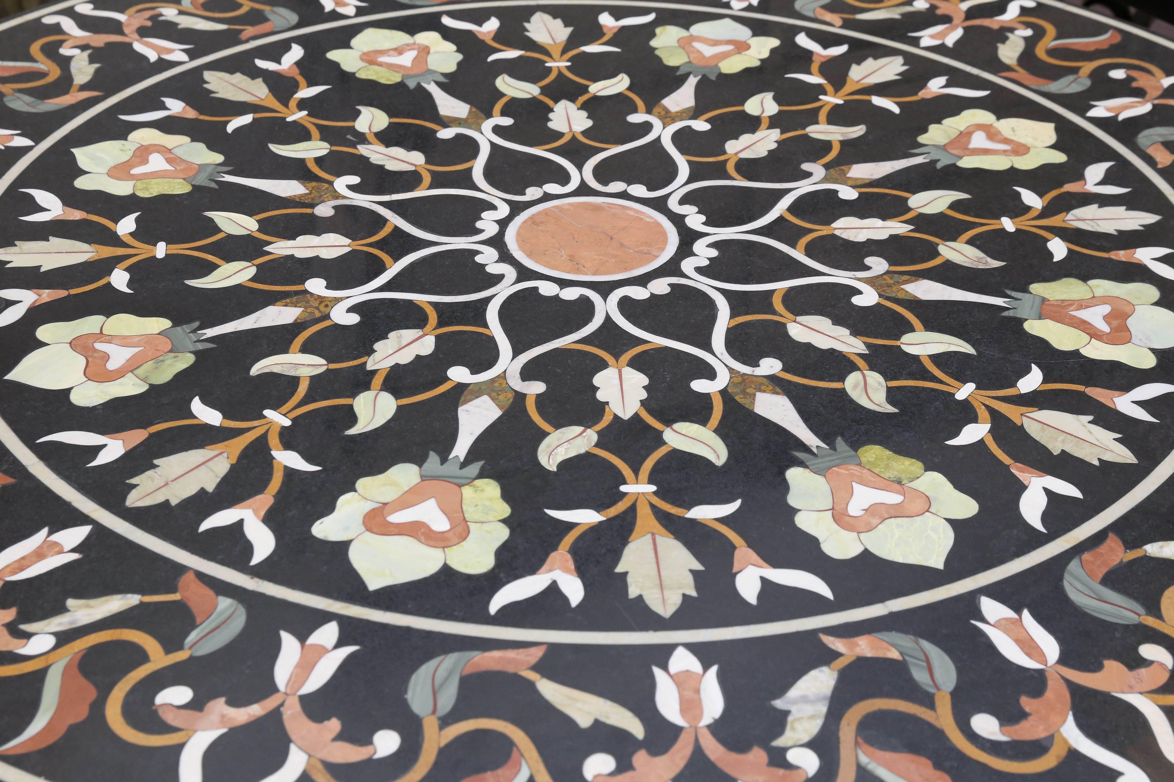 Intricately hand inlaid black marble round center table from central India. The pattern for the inlay design comes from a Persian garden motif. The table is superbly inlaid with rare marbles and semi-precious stones from Afghanistan. It is supported