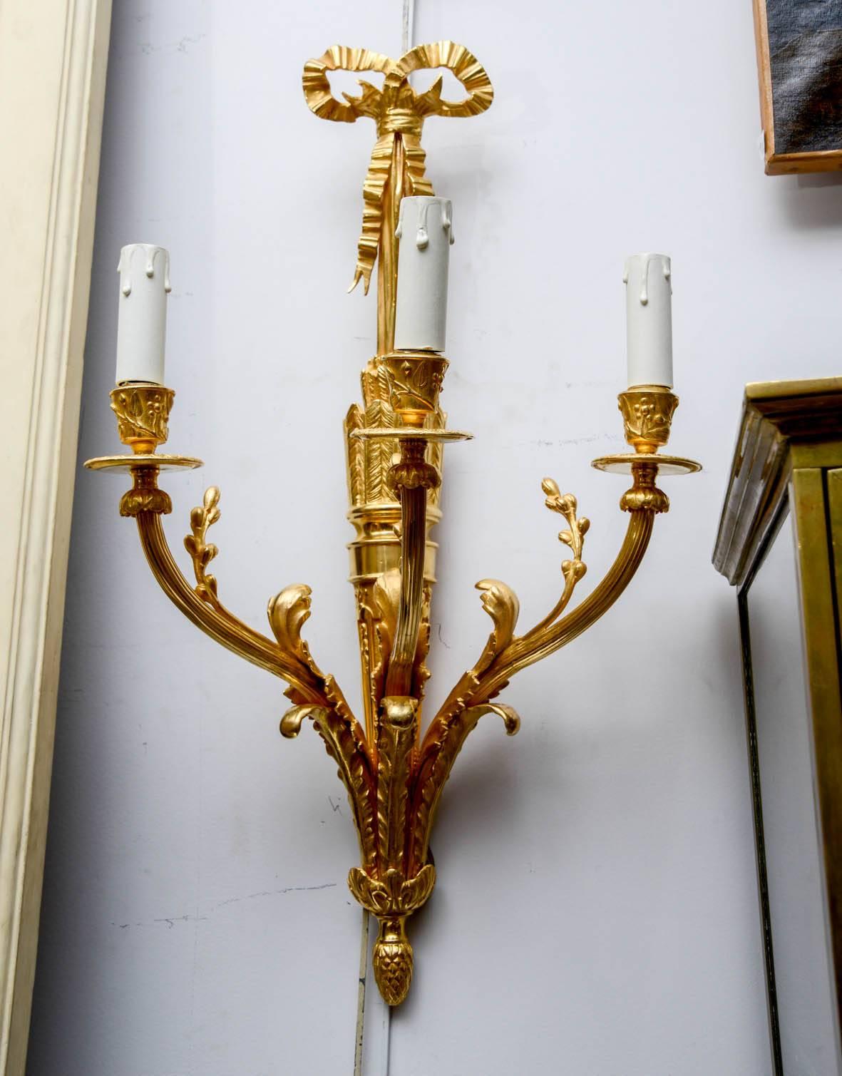 Pair of gilded bronze sconces, three arms of lights in the Louis XVI style.