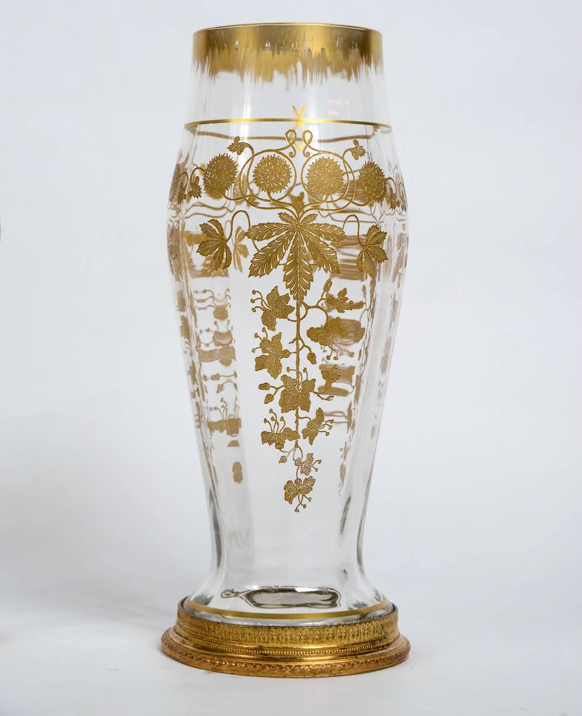 Pair of engraved crystal vases resting on a gilded bronze base.
Gilded engraved floral decor.