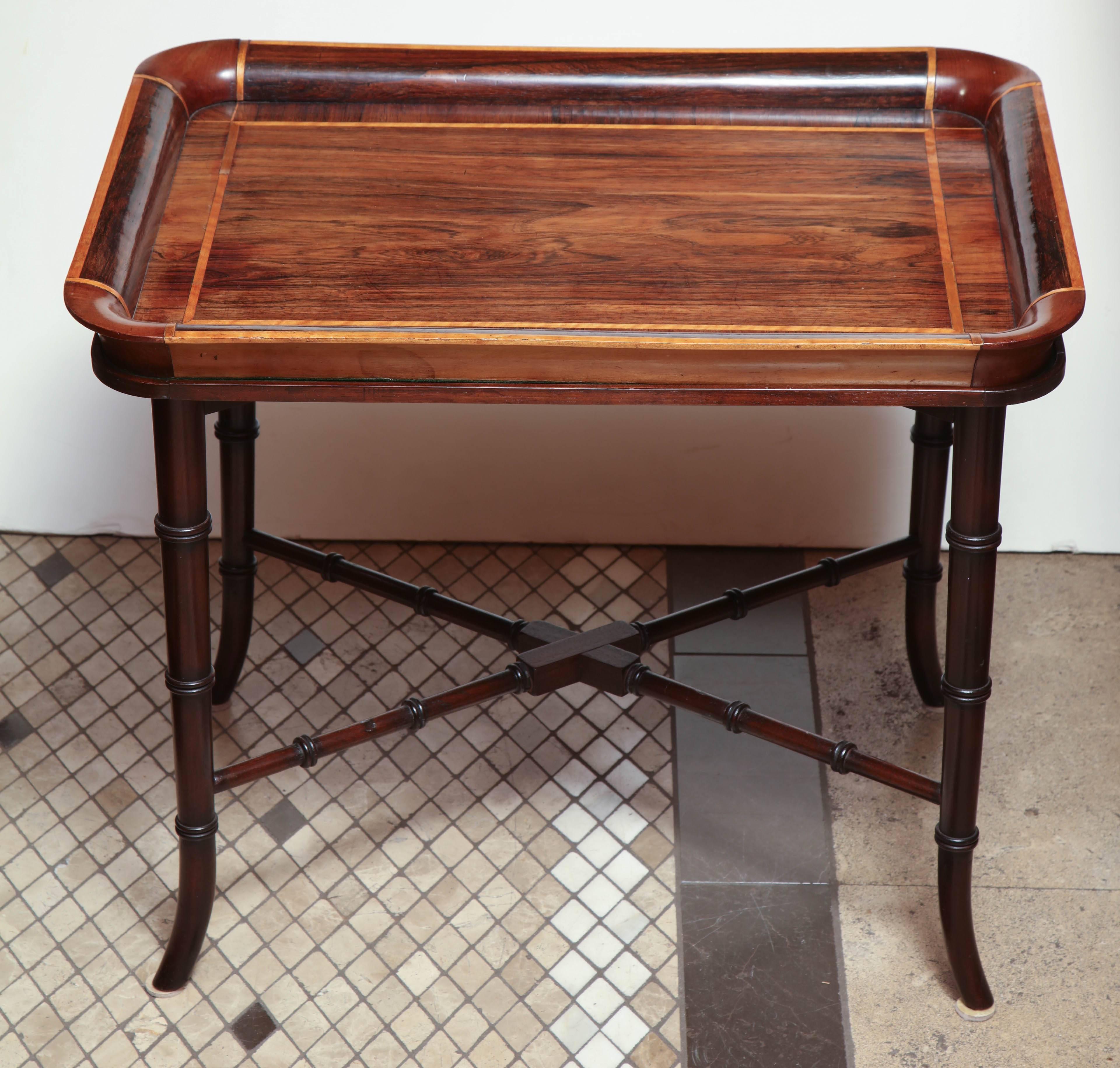 An unusual English late Regency style rosewood tray top coffee table on a later faux bamboo stand with a X stretcher.