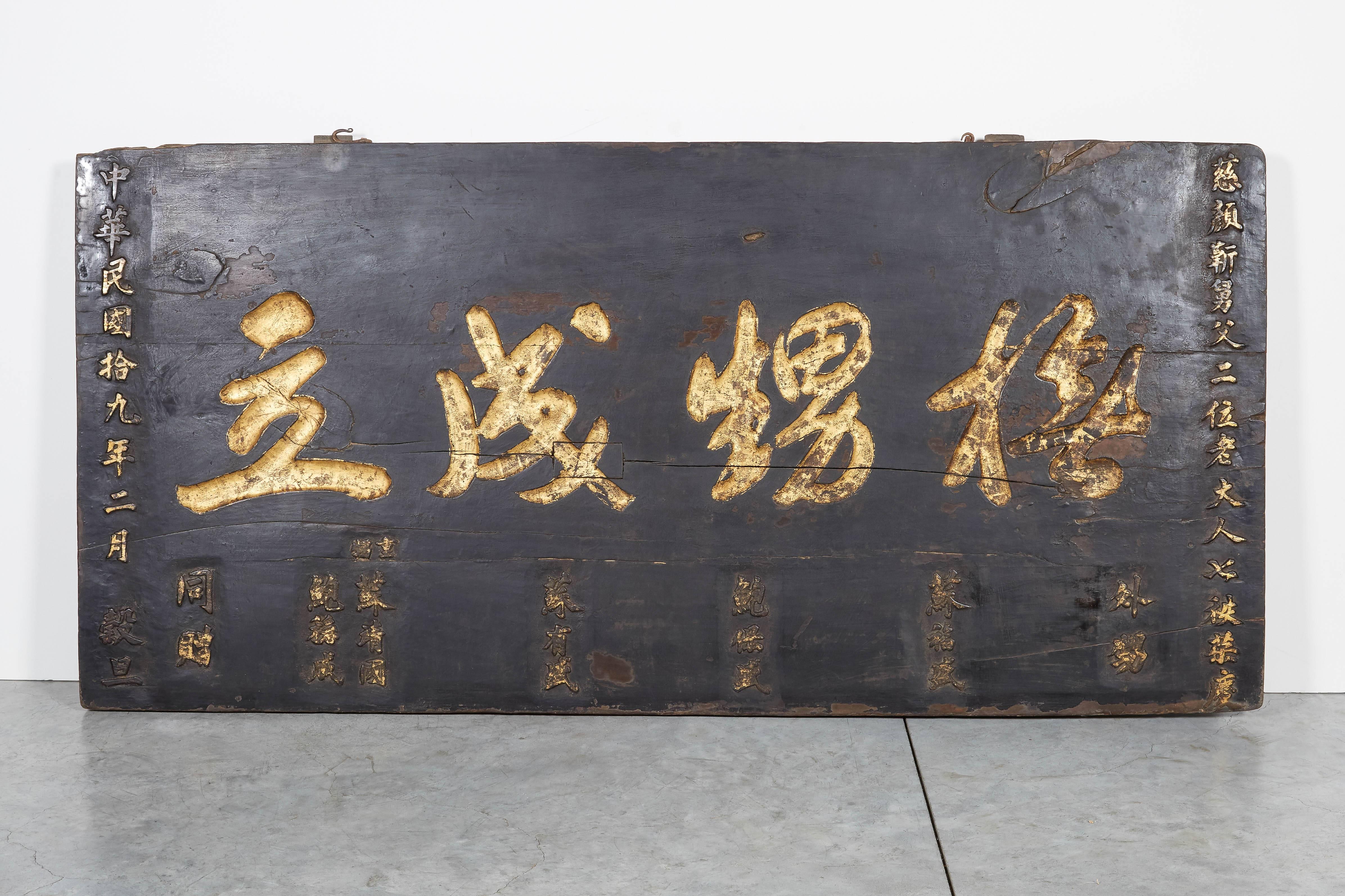 A large antique Chinese sign with striking calligraphy in the center of the sign and smaller Chinese characters all around. Presented in gratitude by a grateful nephew to his aunt and uncle. A beautiful piece with a great story. From Shanxi