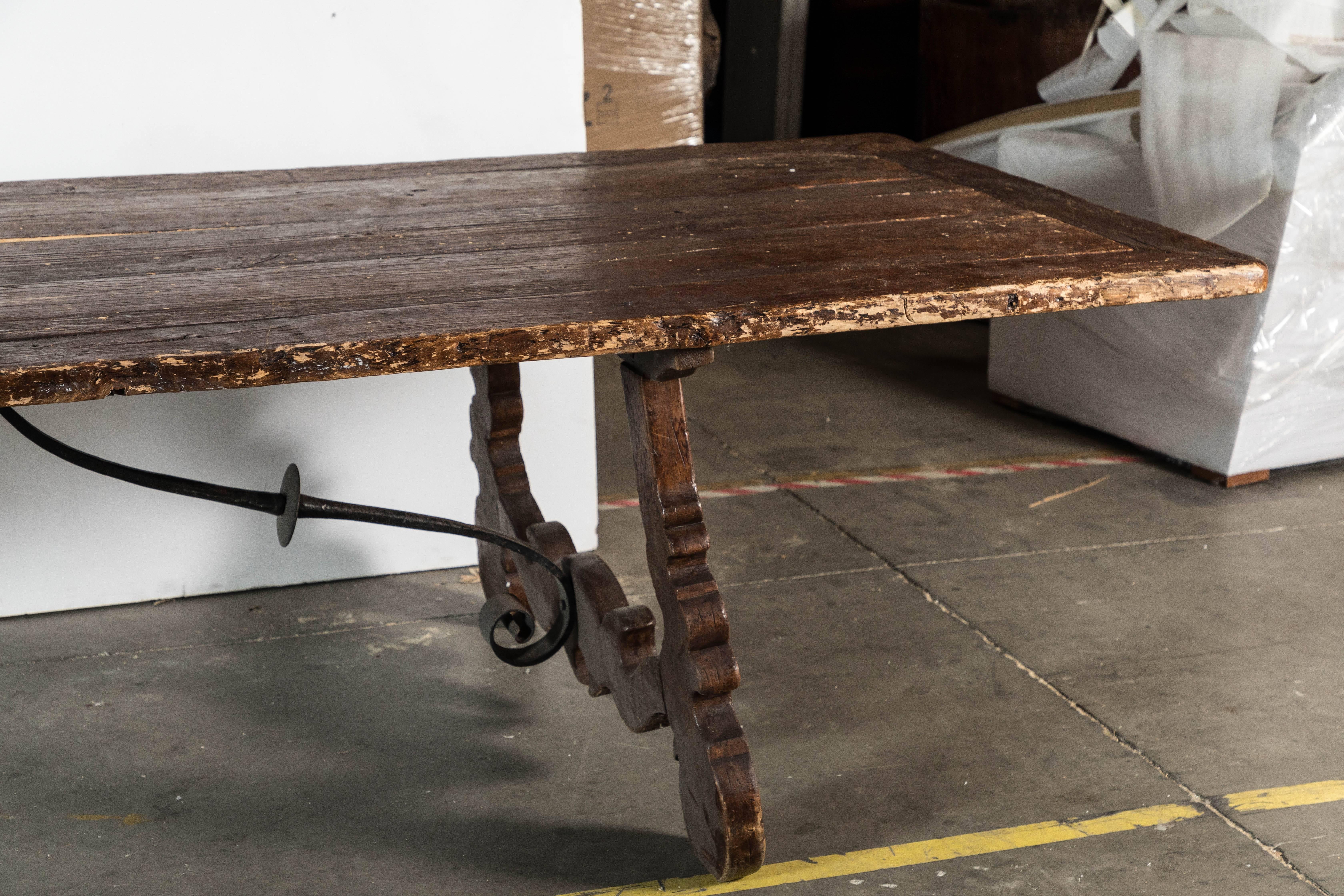 Enormous work table that shows signs of use and wear. Ironwork under the table was added later.