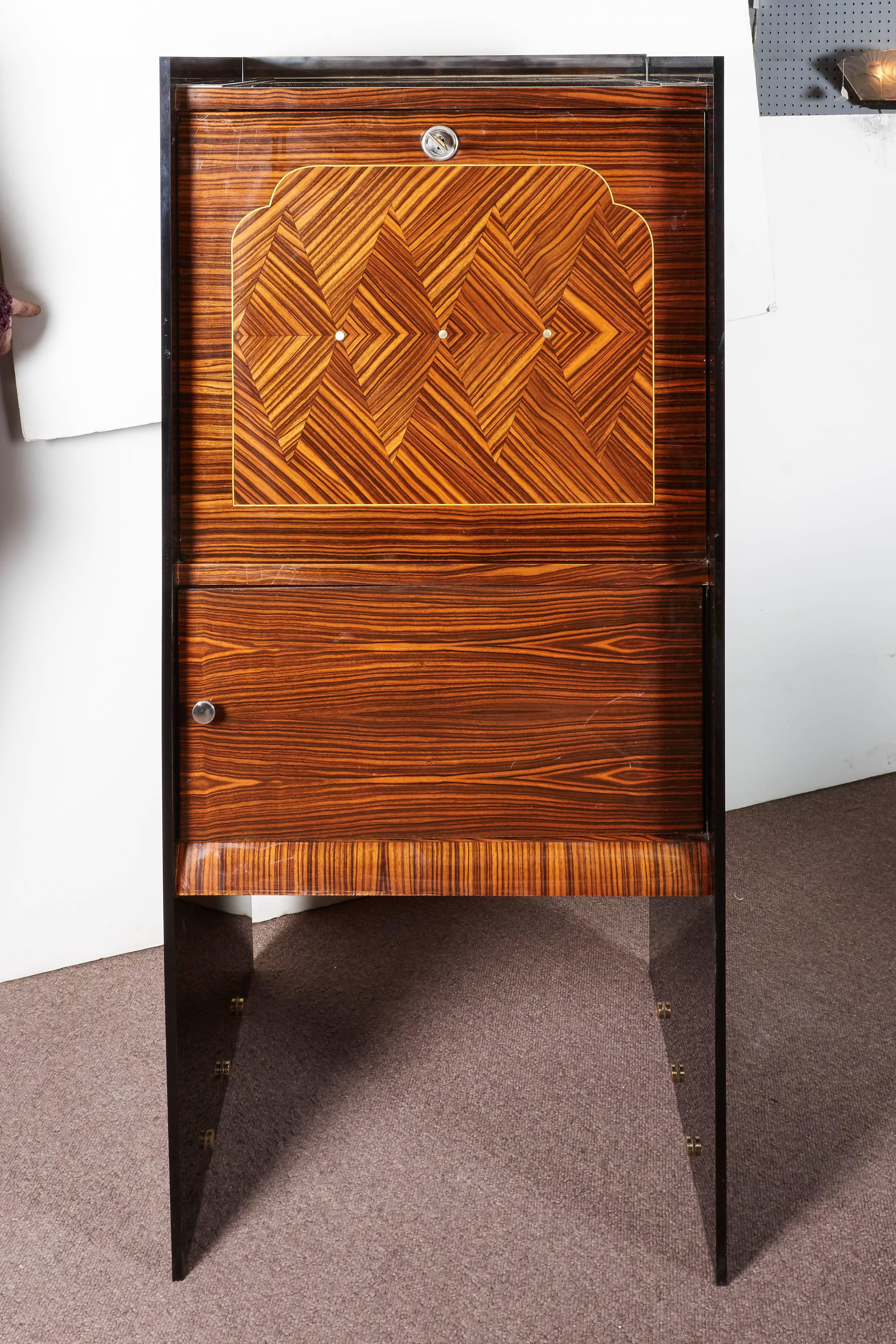 A fine French Art Deco ebene de Macassar drop front bar or secretaire. The exquisite geometric marquetry front door inlaid with mother-of-pearl dots opens to reveal a mahogany interior while the stepped black plexi panels extend the full length of