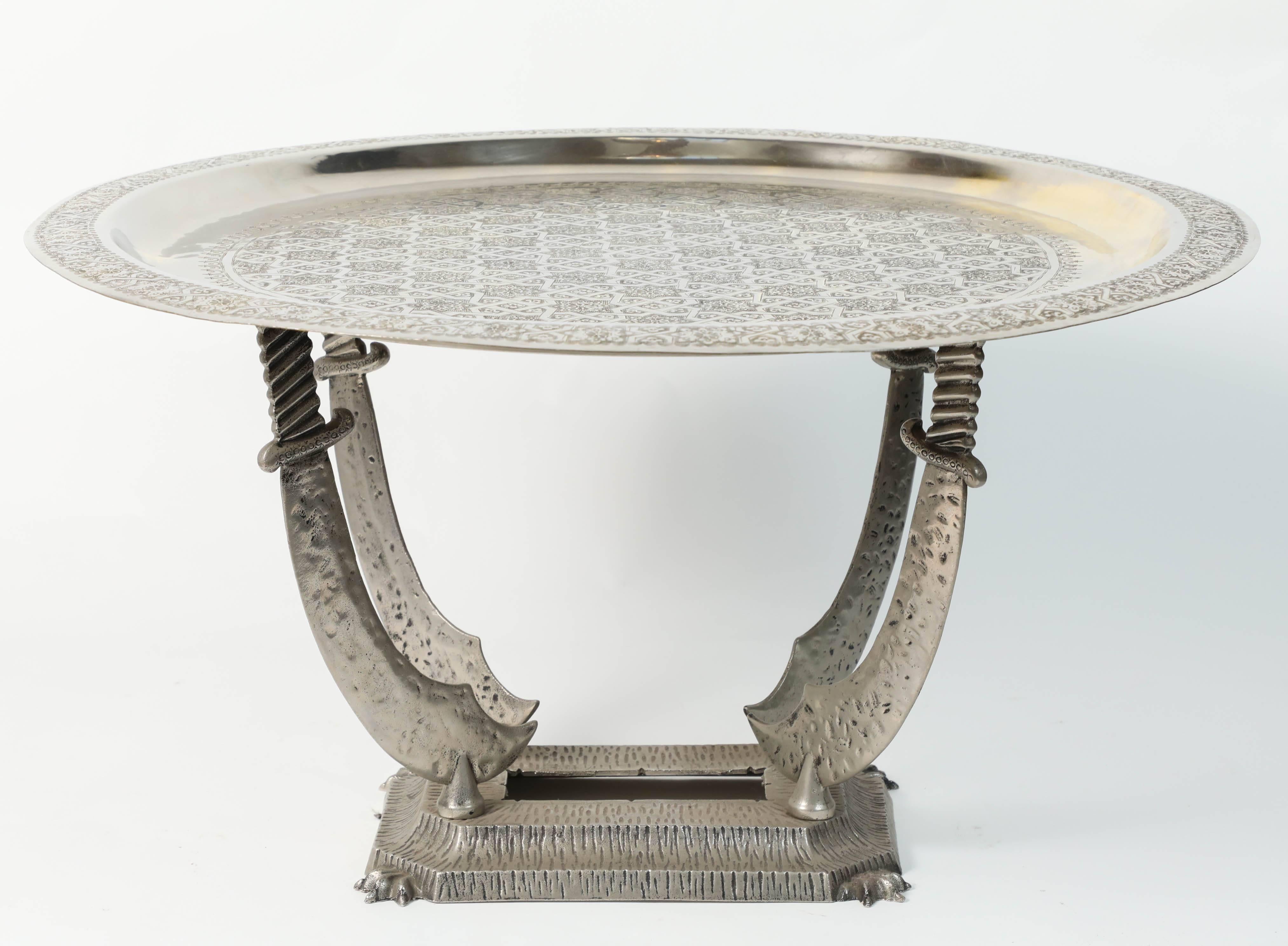Moroccan silver color tray table with Middle Eastern stand made of four standing daggers.
The metal top tray is decorated with Arabic geometric Moorish designs.
The top is removable and consist of a round Moroccan tray on a metal Stand.
Great to