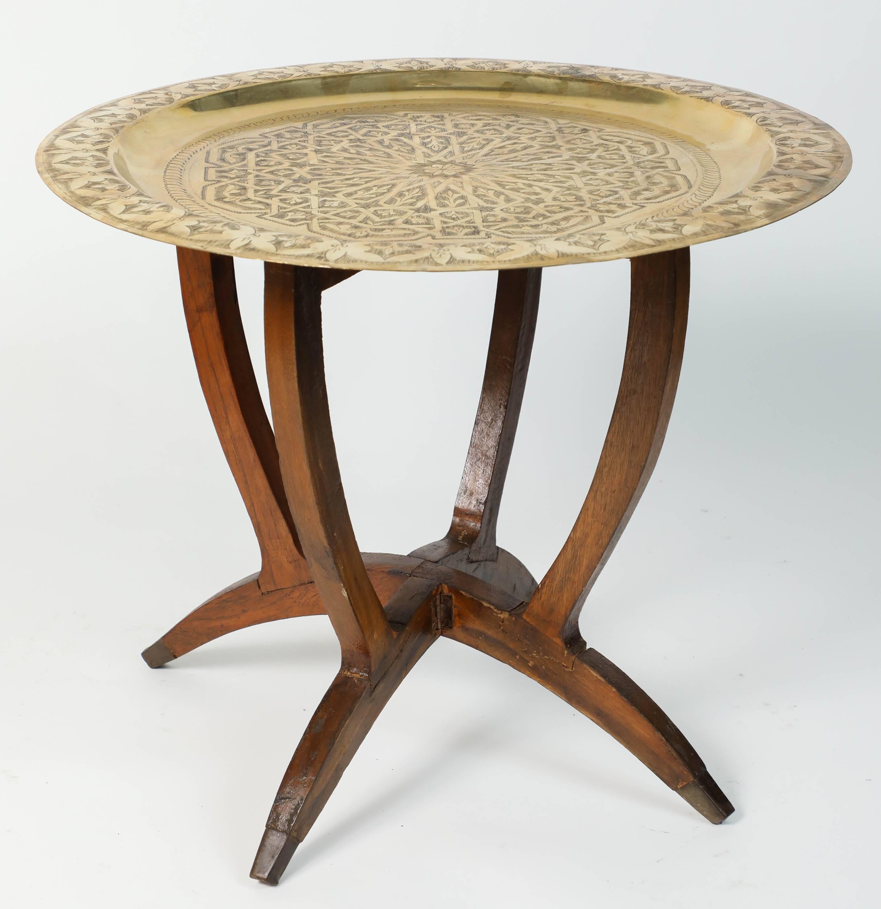 Moroccan round polished brass tray side table. 
Polished Middle Eastern style brass tray, standing on folding base with four legs and brass finals. 
Moorish style hand-hammered brass tray table, Middle Eastern, Moorish style polished brass tray