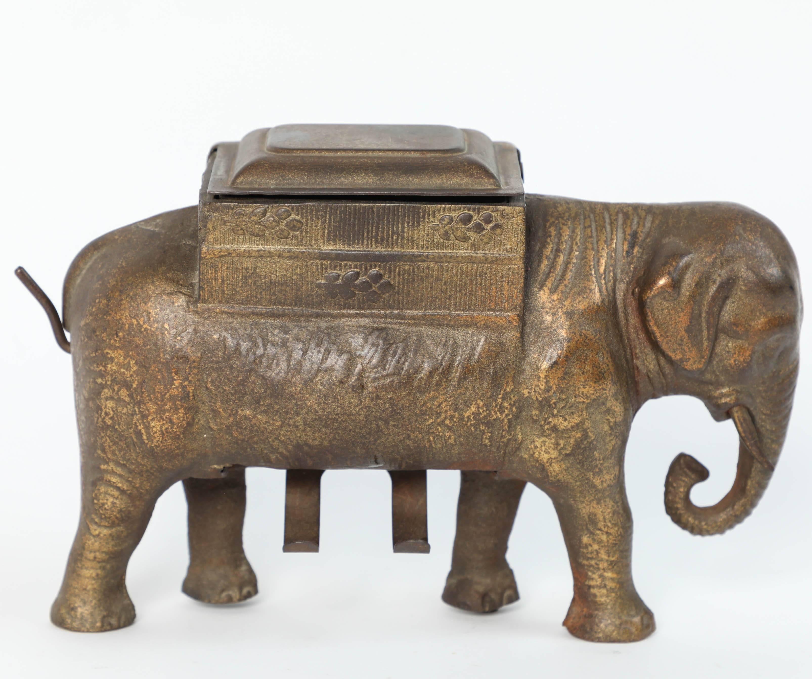 Antique Art Deco heavy cast iron elephant cigarettes holder and dispenser.
This is a nicely detailed heavy piece and in good working condition, brass color finish.
Cigarettes are stored in the trunk on the elephant back.
A turn of the tail drops