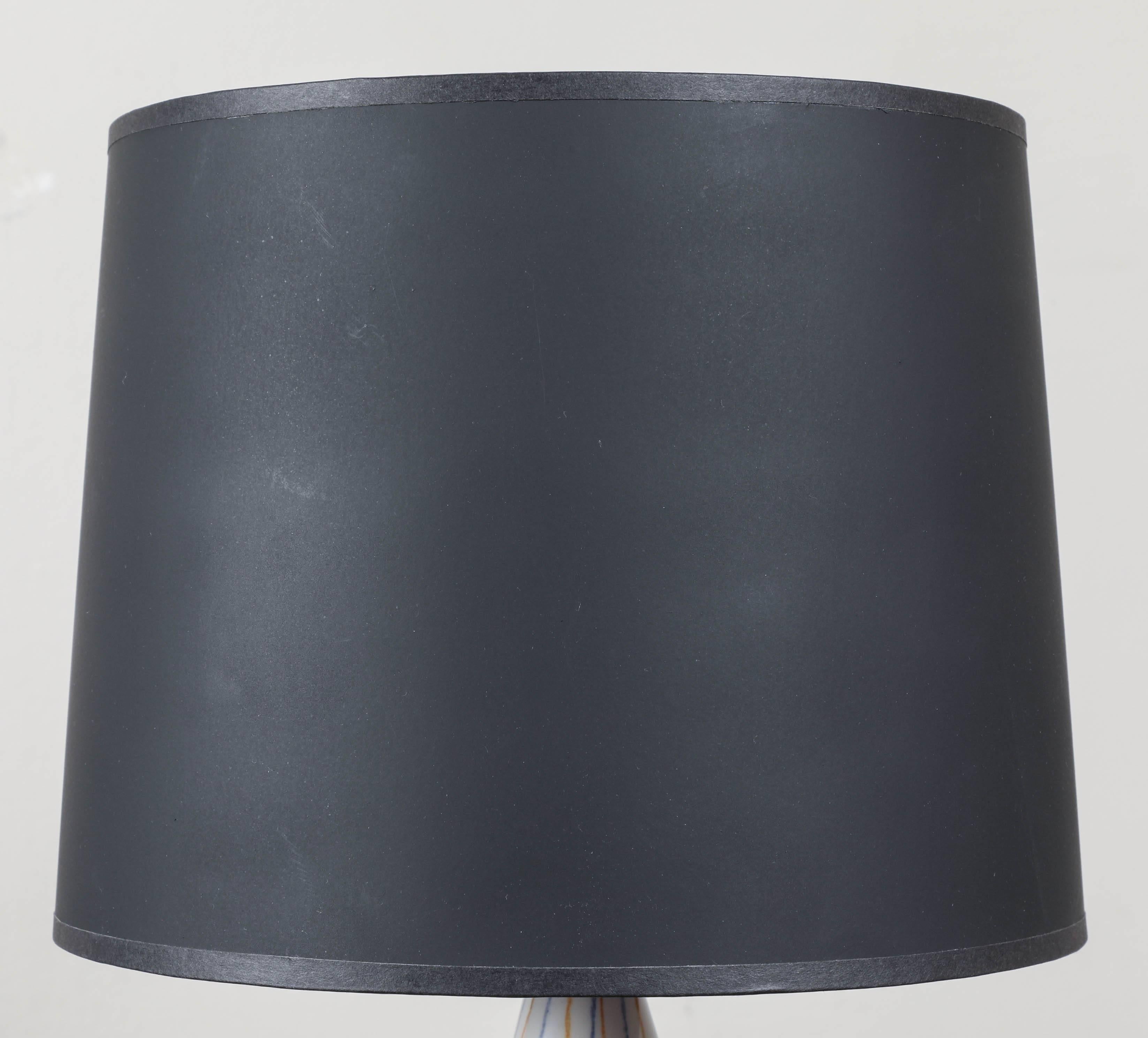 A small painted ceramic table lamp with ebonized black wooden base. Updated and “Americanized” hardware. Custom black paper shade with blue interior.
 