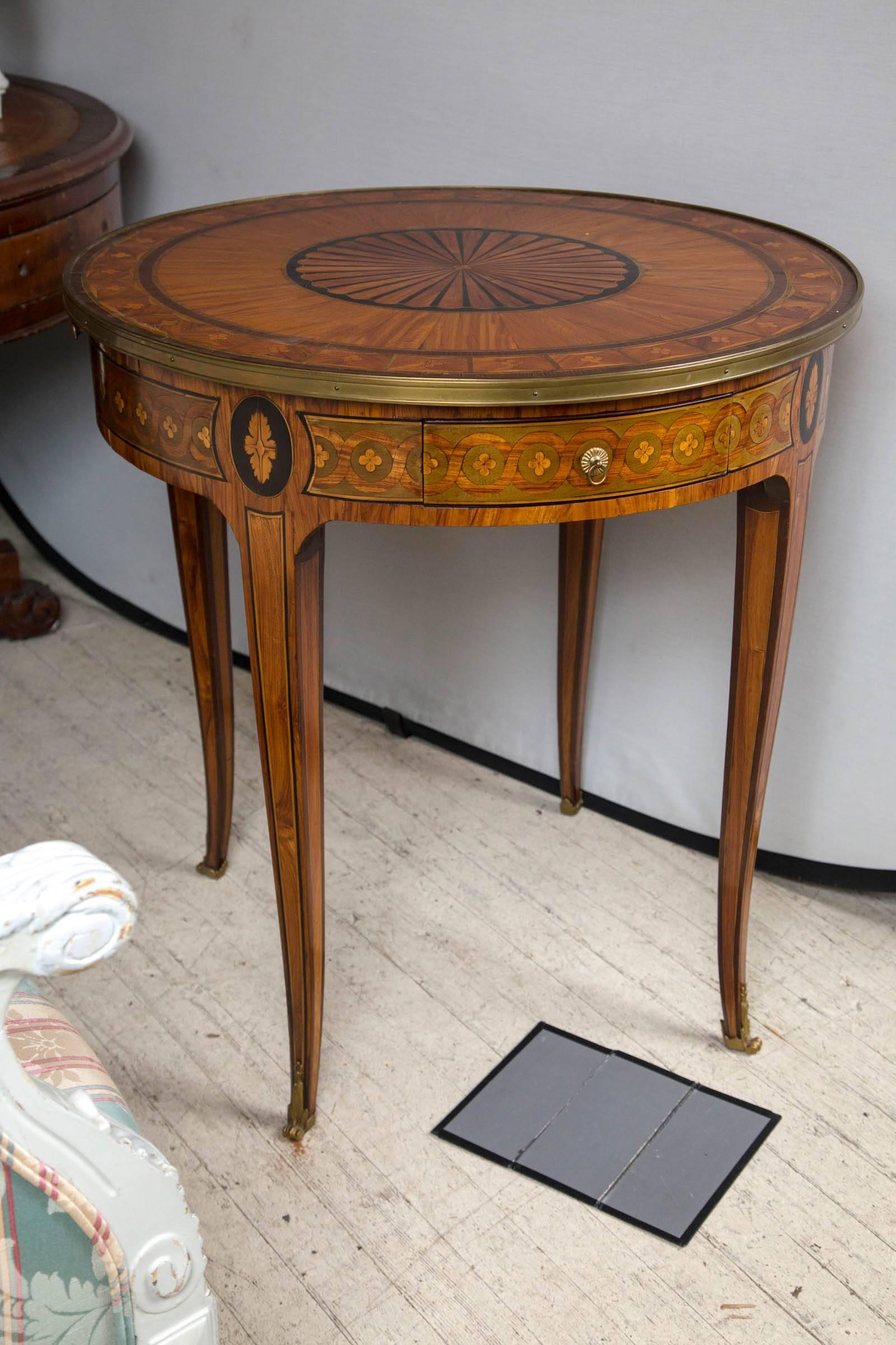 A fruitwood table with ebony, sycamore and satin wood marquetry. In the transitional style. (Louis xv-louis xvi) there are two opposing drawers and two opposing candle slides. Tapering legs ending in bronze sabots. Brass ring pulls. Brass edge.