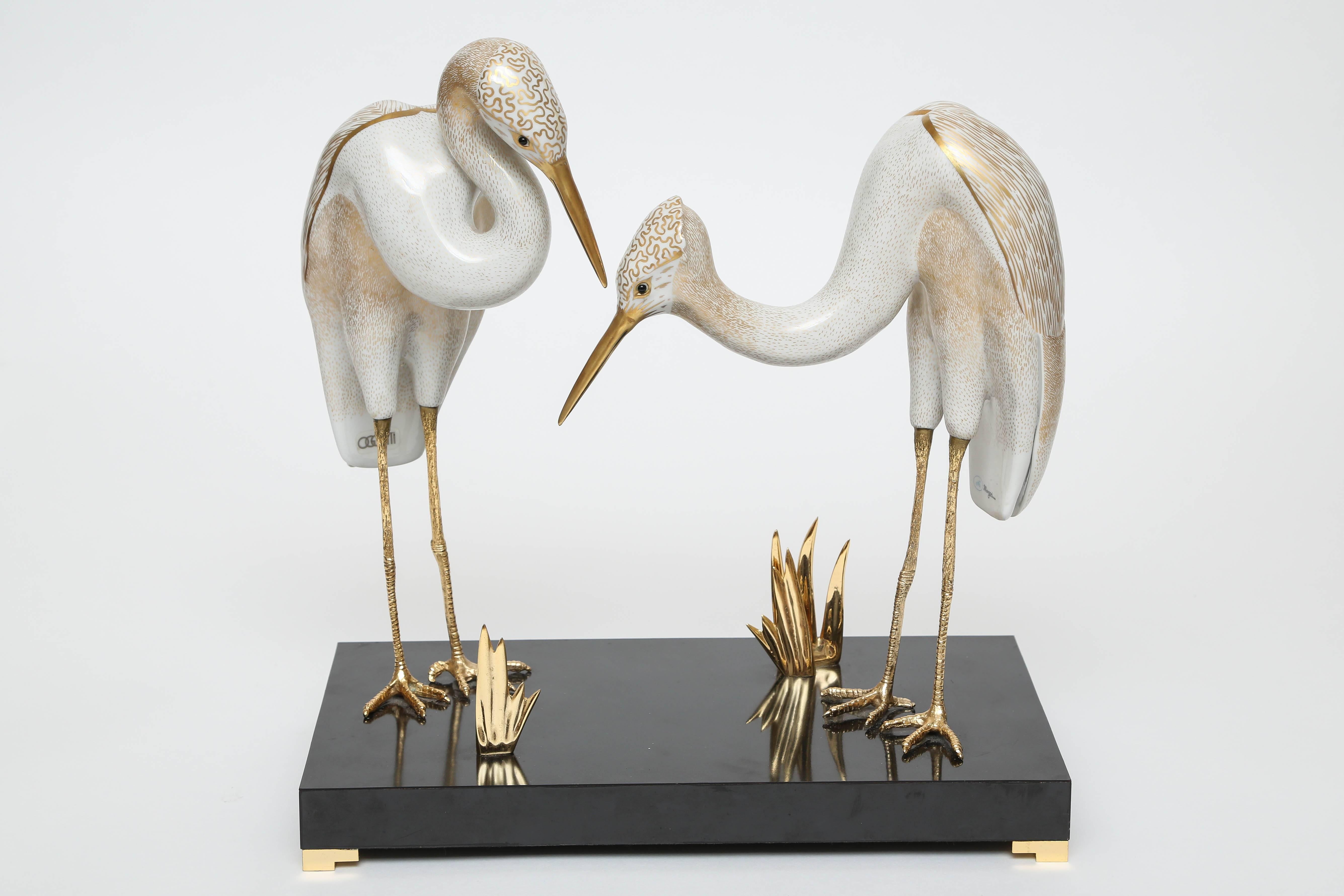 Elegant pair of porcelain birds by Mangani for Oggetti. These birds stand on gilt bronze legs with 24-karat gold trim.