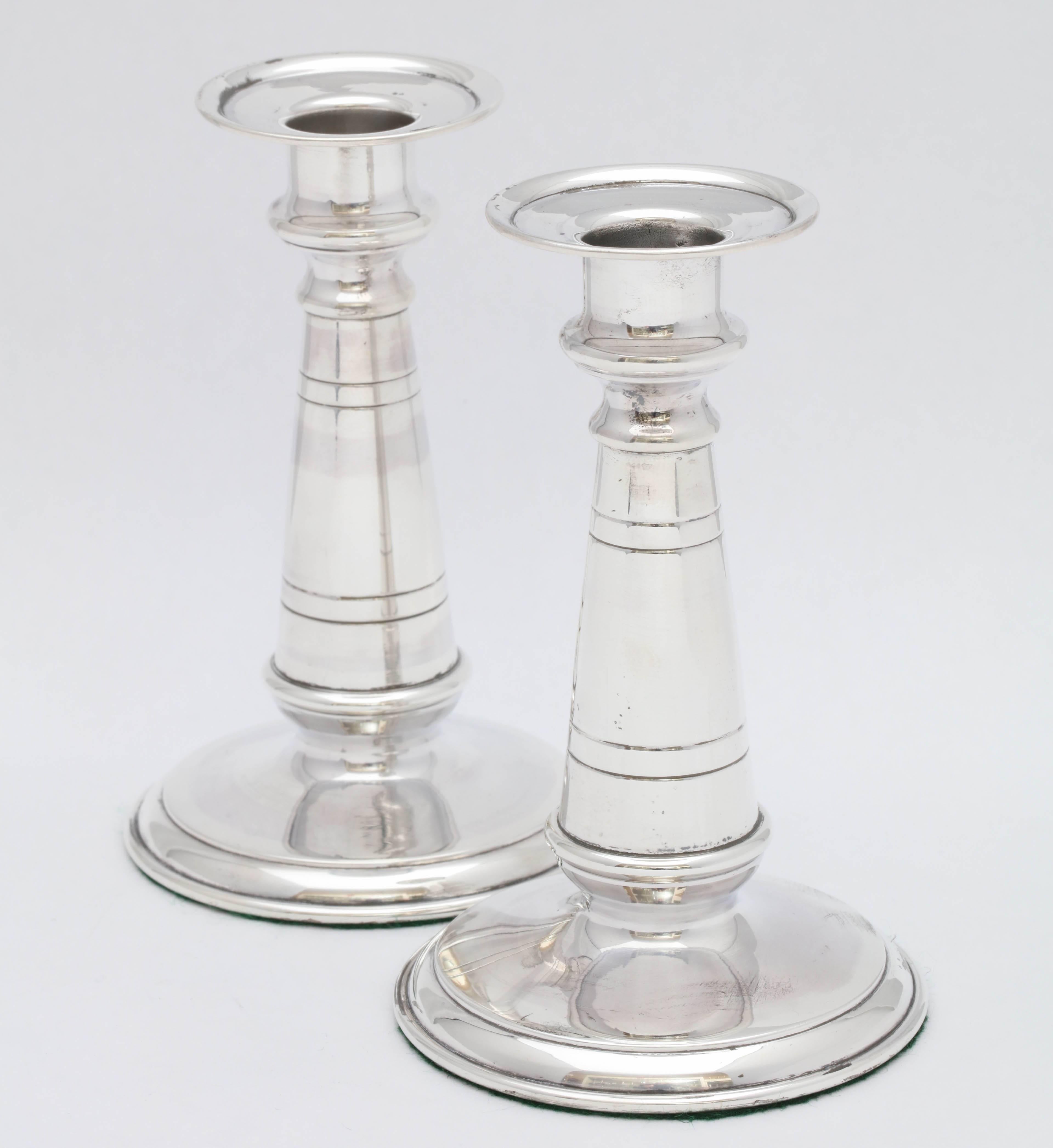 Pair of French, Empire, sterling silver candlesticks, Paris, circa 1850. Measures: 5 inches high x 3 1/8 inches diameter across base x 2 inches diameter across candle cups. Weighted. Dark spots in photos are reflections.