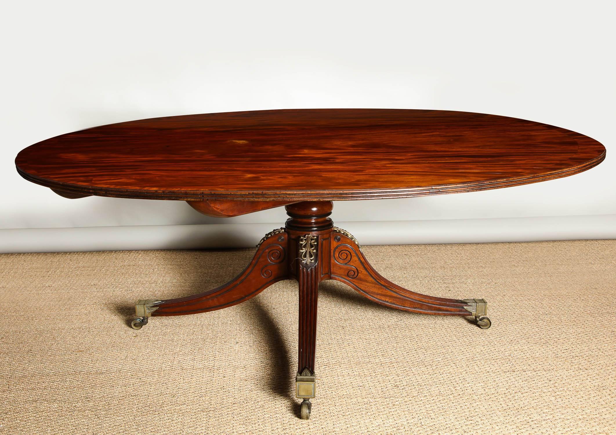 Very fine Regency period dining table, the circular top in well figured mahogany, having wide mahogany banding and ribbed edge over turned mahogany pedestal with ebonized rings and standing on bronze mounted and saber legs having incised ebonized