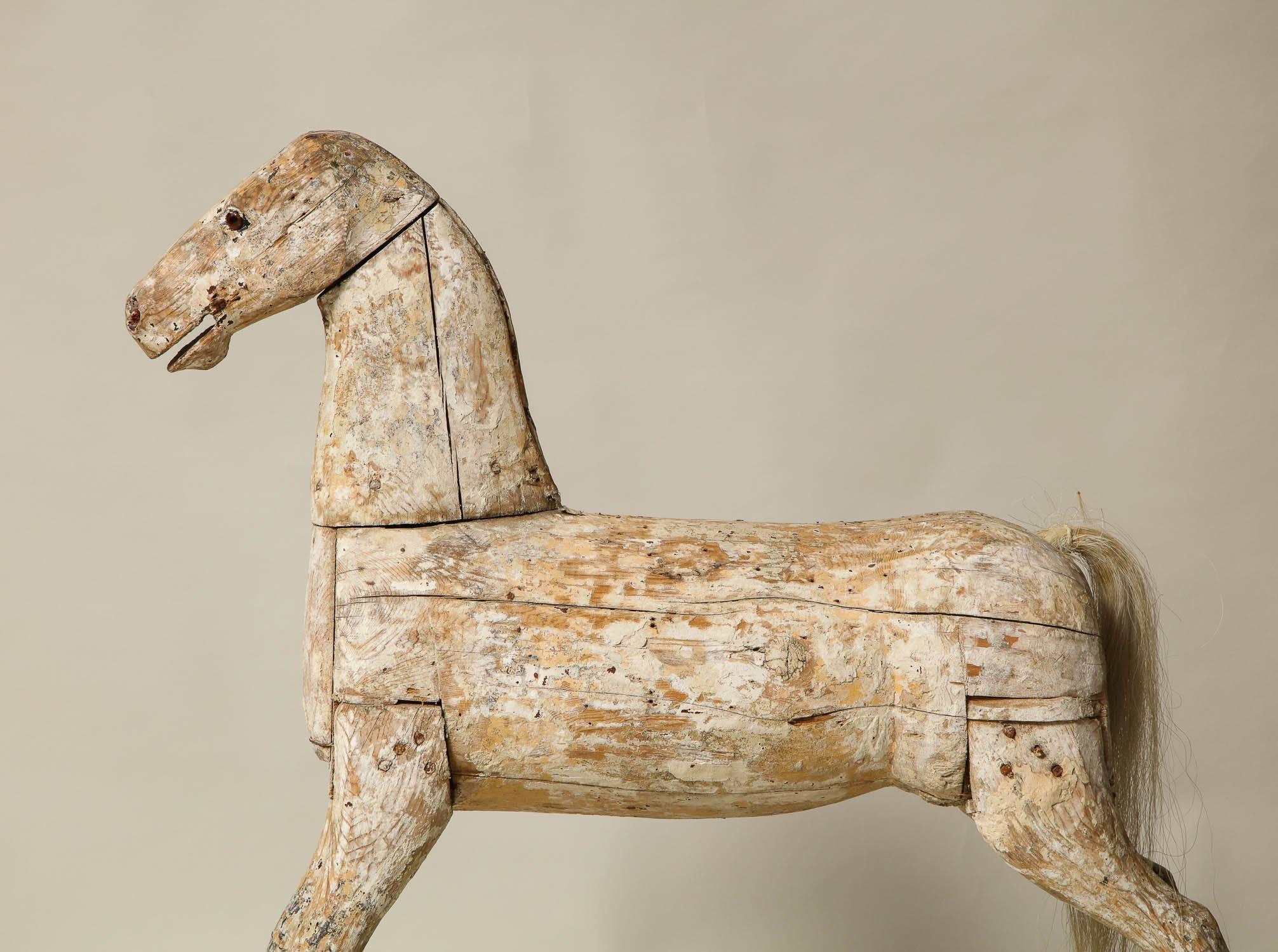 A sculptural, hand-carved 19th century folk art rocking horse in its original chalk white paint on carved and auburn painted rockers. This horse possesses an alert and lively stance, and an original distressed painted surface.  He is a fine piece