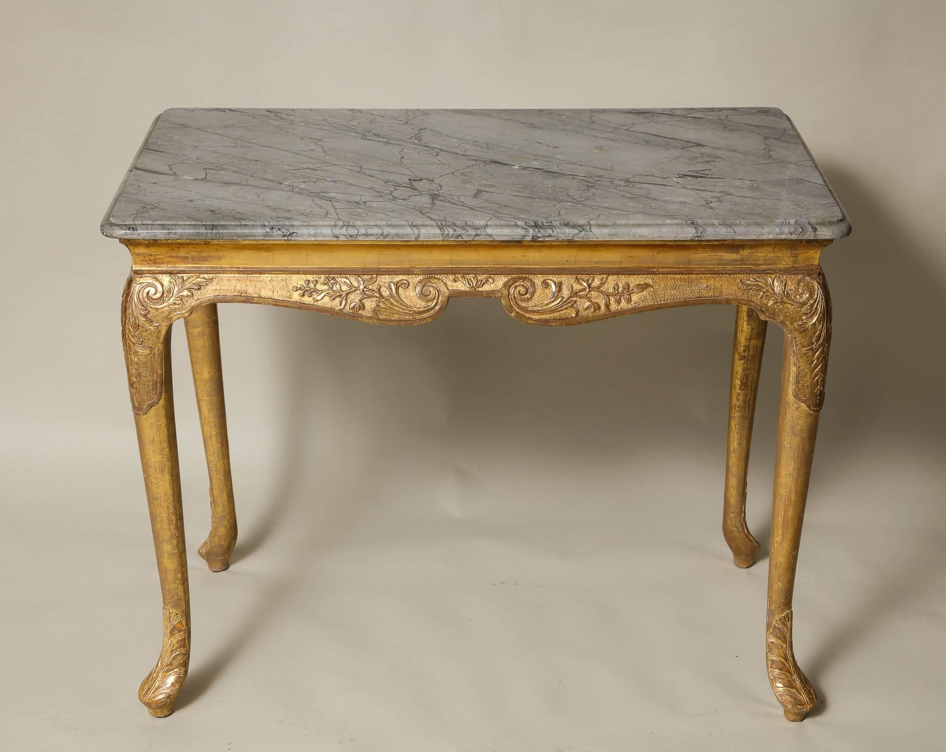 George I gilt side table with grey marble top. the apron, knees and feet with foliate and punch-work carved gesso in burnished water gilding on a matte gold ground, circa 1730. The top later.