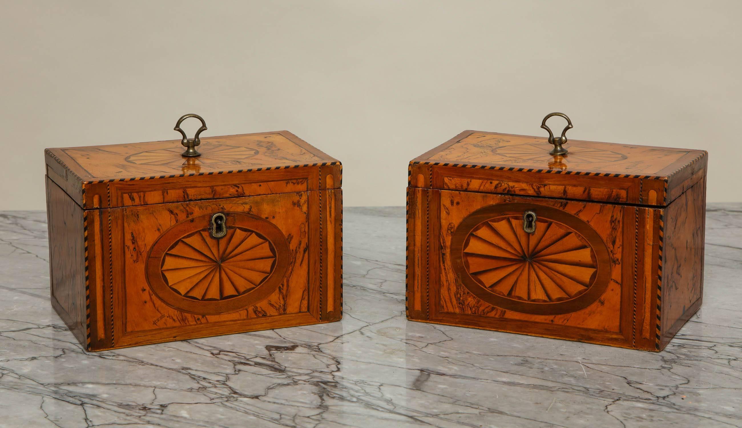 Unusual pair of George III boxes, having patera inlaid tops and fronts on a spalted walnut ground and with original gilt lacquer axe head handles, one fitted with two compartments, the other as a large, undivided interior, both retaining original