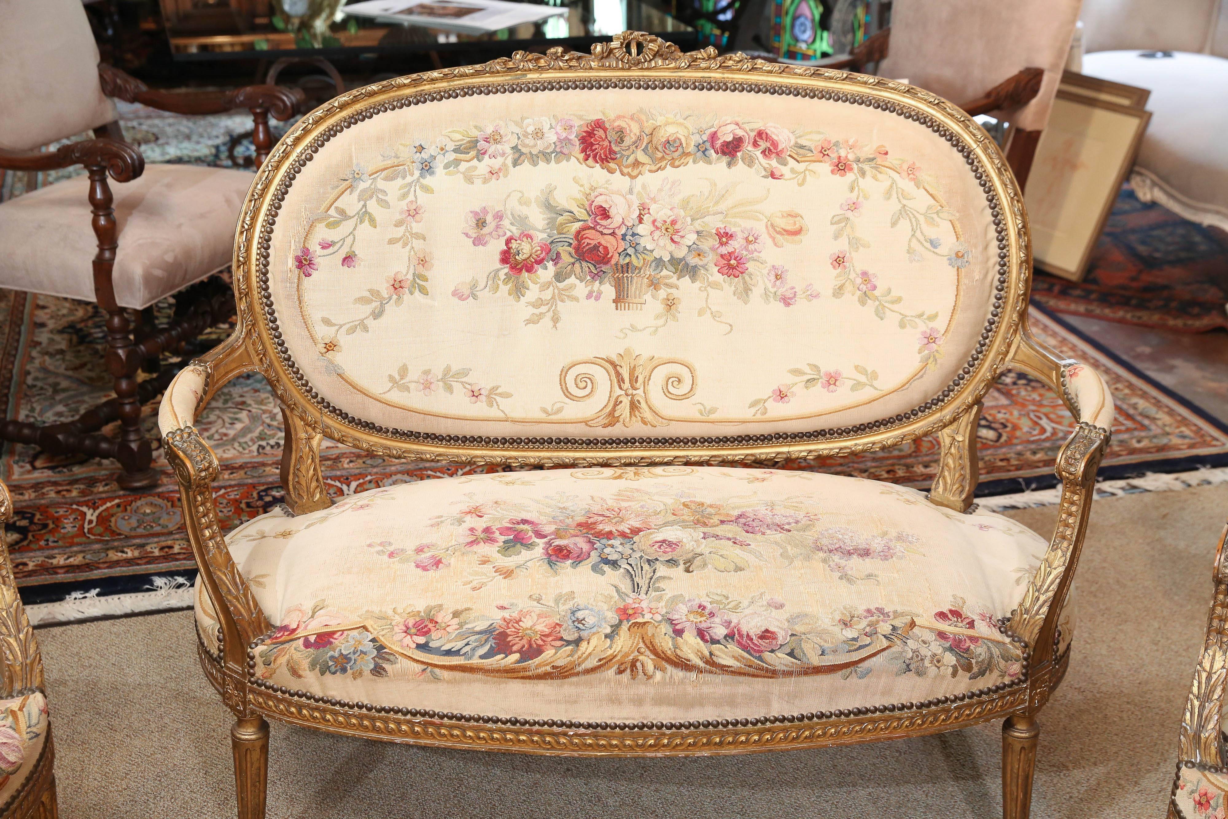 Lovely giltwood settee with matching armchairs.
Aubusson original upholstery in a floral pattern.
Gold background color with a rosy red and lavender
flowers. Oval shaped backs. Original gilding with wear
commensurate with age. The upholstery is