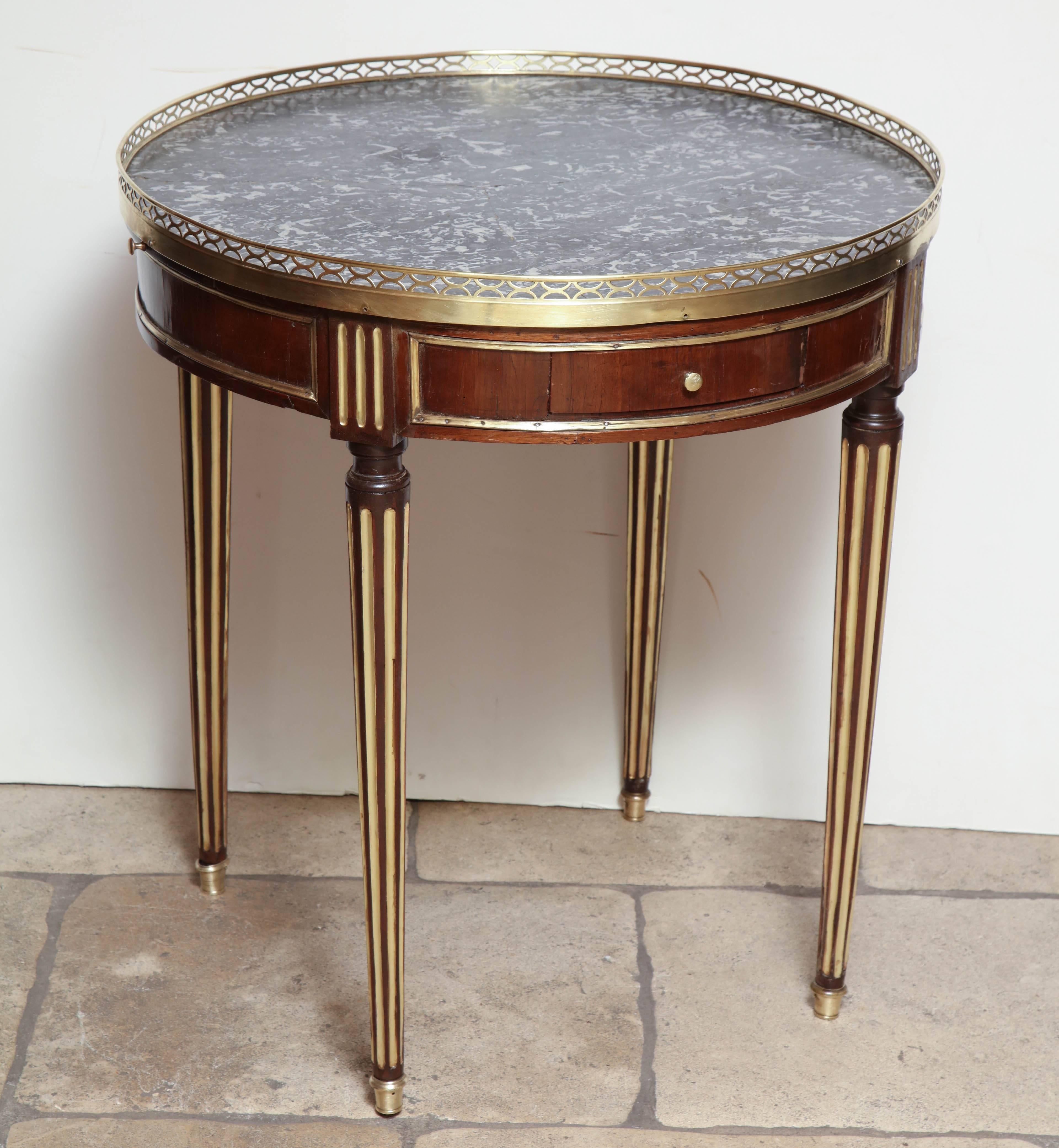 French Louis XVI marble-top Bouillotte table with a pierced bronze gallery, brass and gilded trim on bronze feet.