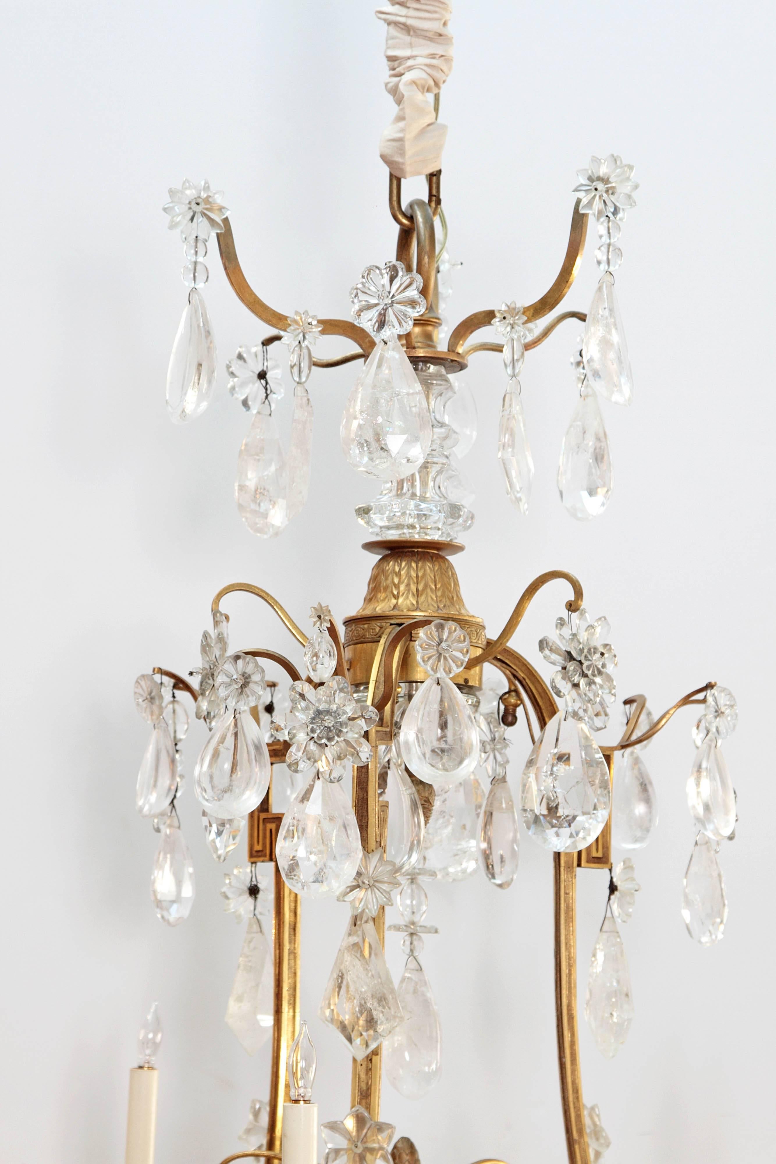 A large rock crystal and ormolu Louis XV style chandelier, nine (9) lights on three (3) tiers, with central post of ormolu and crystal, curving arms form a Greek key design with multiple large rock crystal drops

Sold in 1974 by Nesle, Inc. Fine