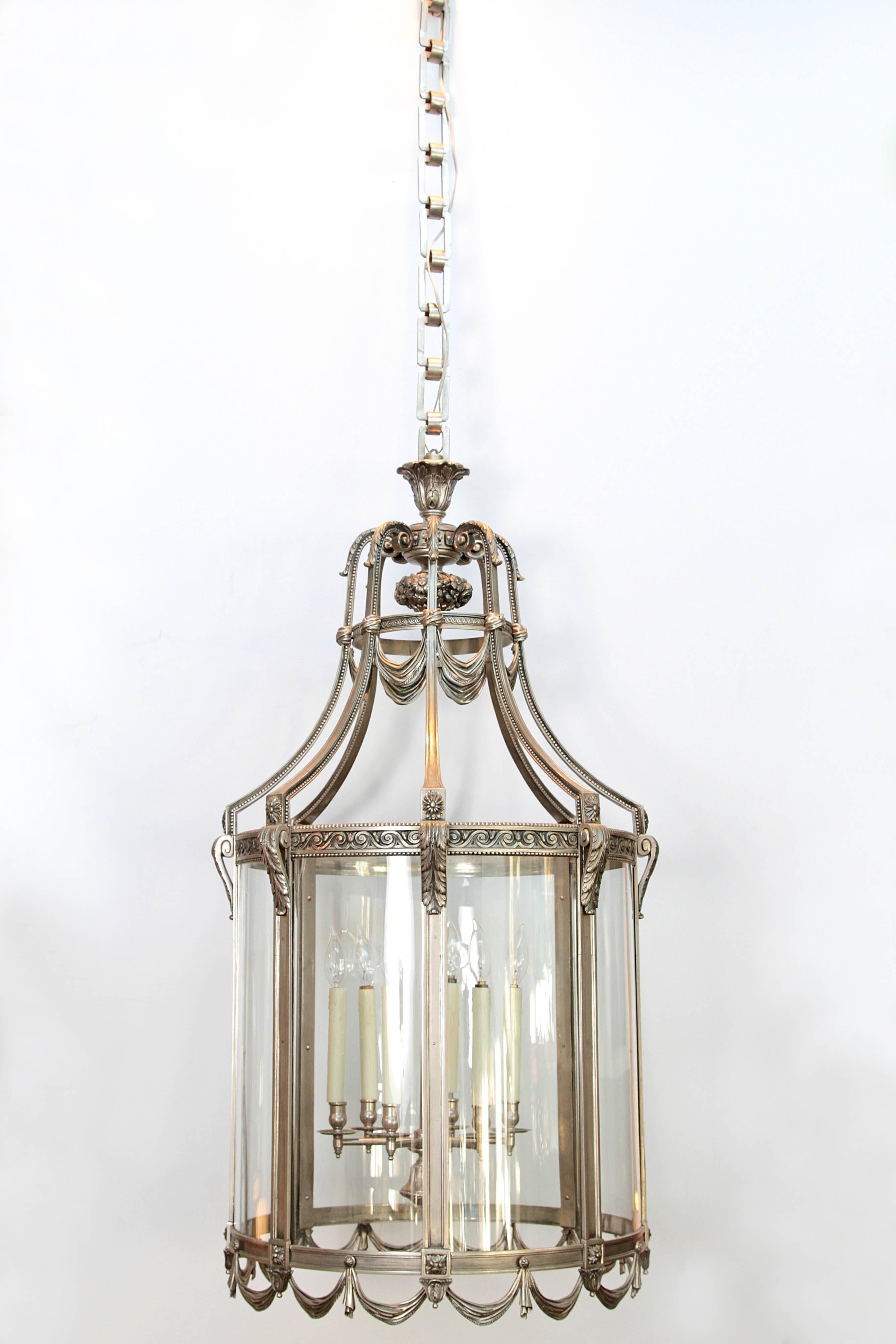 A very large finely cast nickel-plated bronze Art Deco lantern. The top is a basket of fruit with swags and curving supports. The eight (8) glass panels are framed in bronze with swags along the base. Centre has a cluster of six (6)