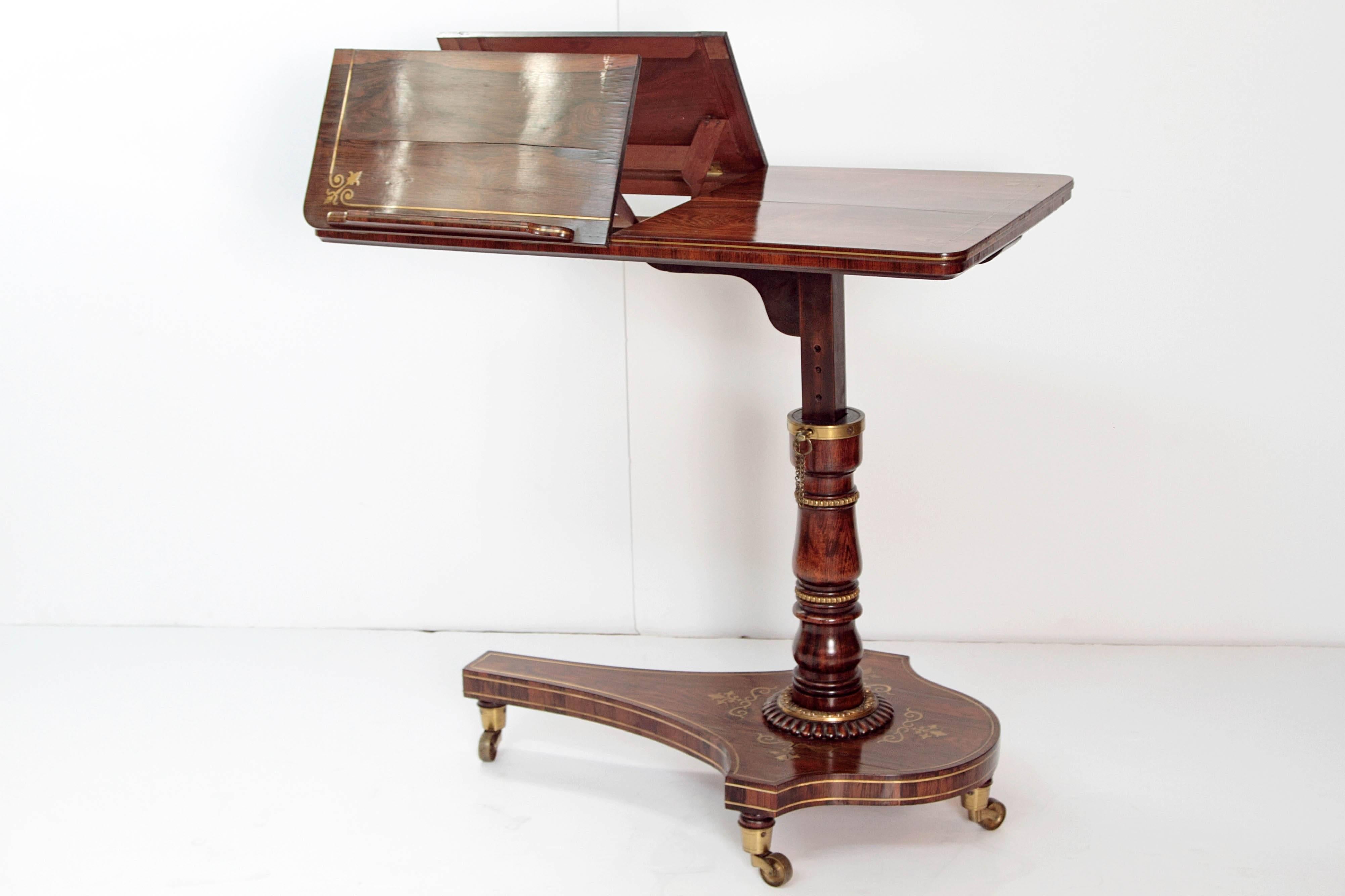 An English Regency adjustable bed table / dual reading stand of rosewood with inlaid brass decoration, rectangular top with rounded corners of bookmatched rosewood, two (2) hinged sections opposite one another each with ratchet easels for a book or